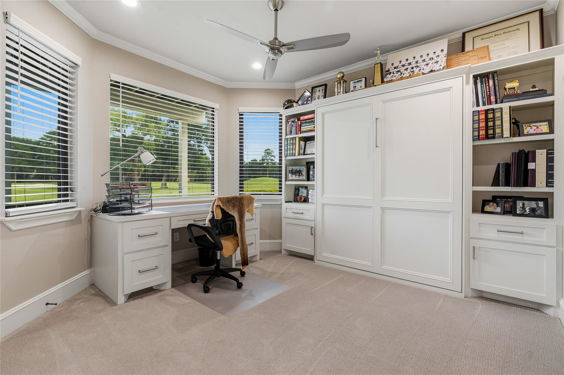 75 Huntsmans Horn Circle, The Woodlands, TX 77380 Bright and inviting home office featuring large windows with serene views, built-in shelving, and a sleek Murphy bed for versatility.