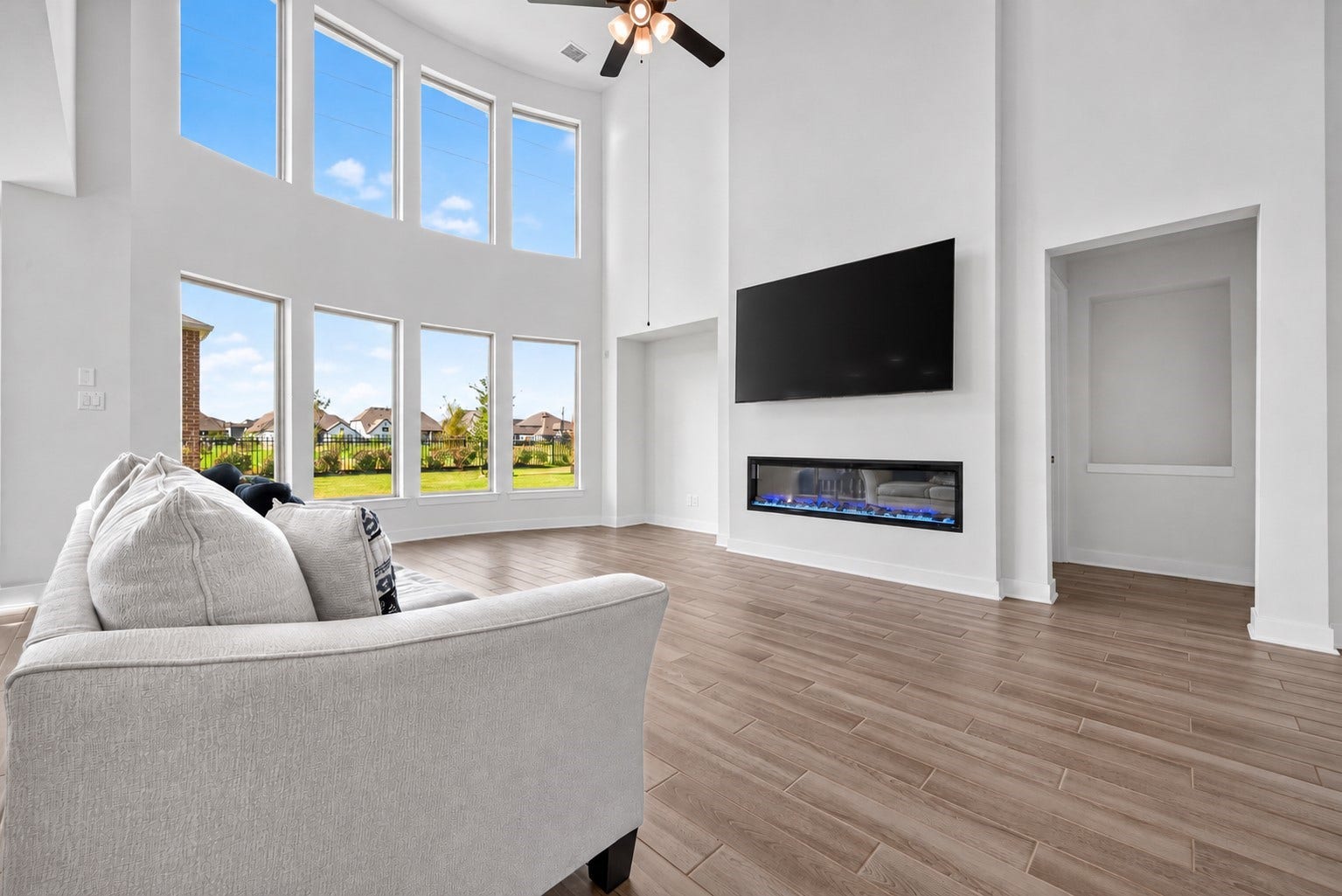 2511 Falling Fig Lane, Richmond, TX 77406 A grand, open-concept living space featuring soaring ceilings, a dramatic wall of windows, and a sleek electric fireplace that sets the scene for elegant entertaining, cozy evenings, and unforgettable moments in a truly inviting atmosphere