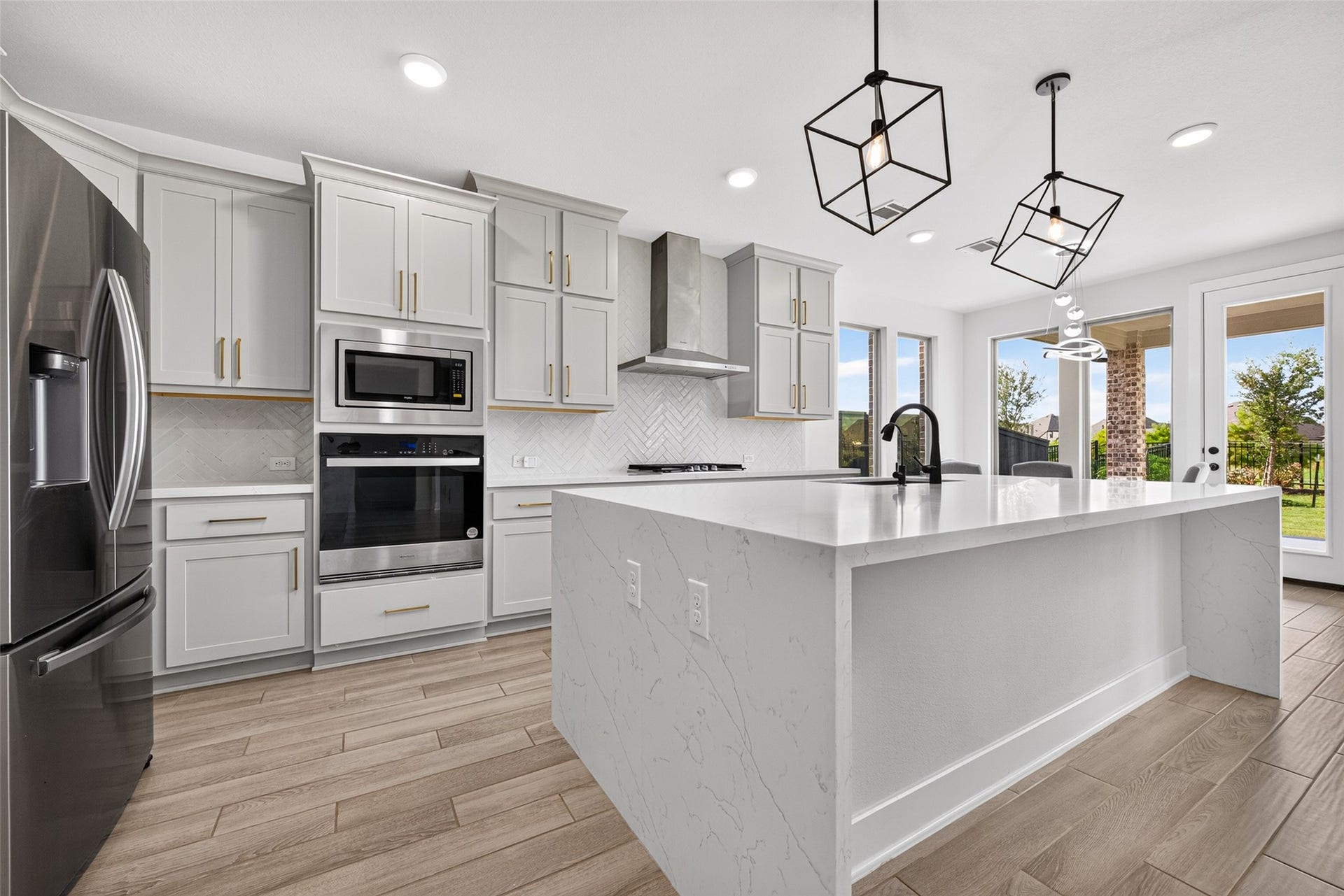 2511 Falling Fig Lane, Richmond, TX 77406 A luxurious chef-inspired kitchen showcasing built-in appliances, a stunning waterfall quartz countertop, and upgraded Shaker-style cabinetry accented with elegant hardware and crown molding, blending timeless design with sophisticated modern appeal