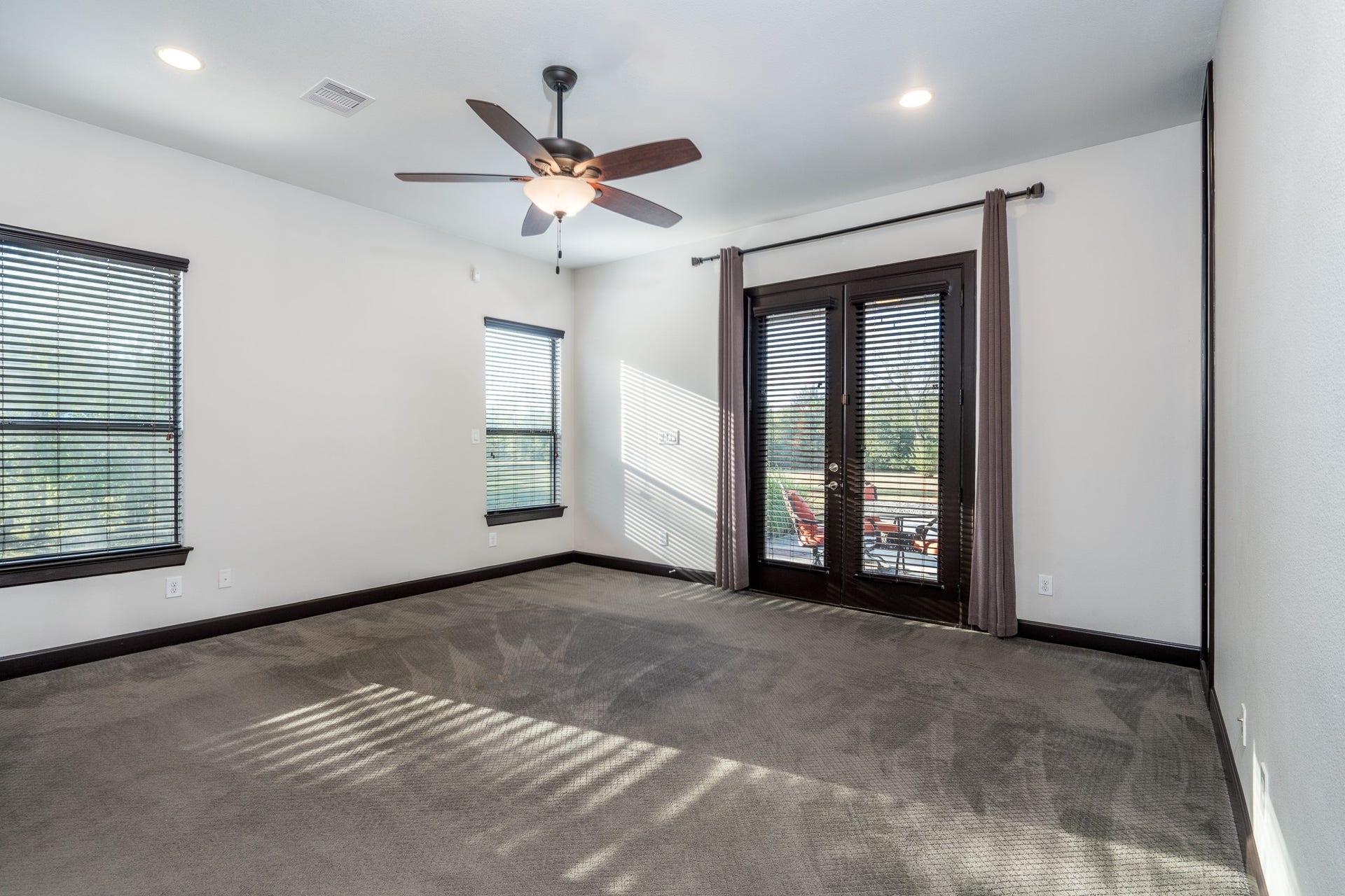 Primary bedroom on the first floor has walk-out French door access to the covered patio and pool area.