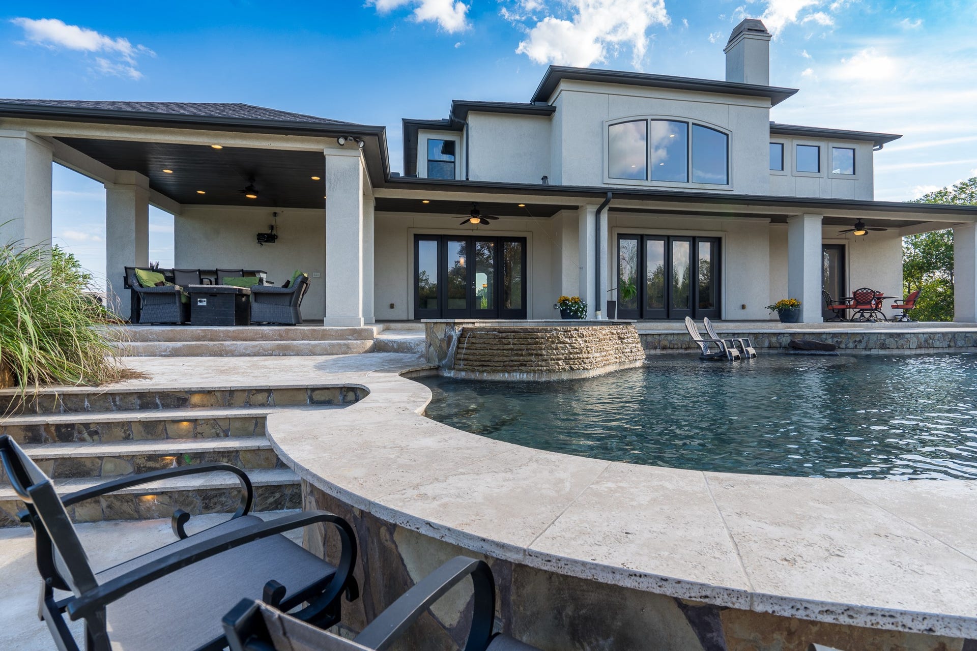 Travertine ledge morphs into a serving space at the raised bar conveniently located next to the summer kitchen.