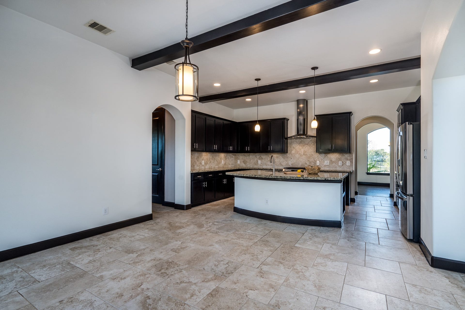 The beamed ceiling continues into the nearby island kitchen.
