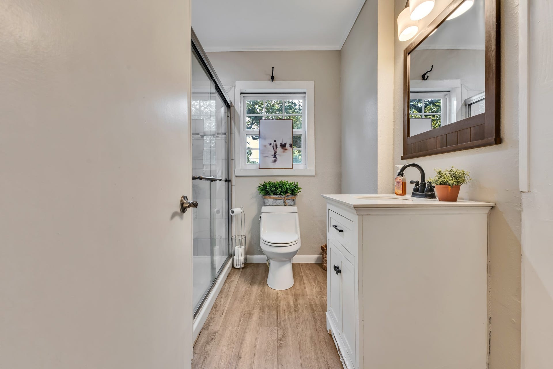 801 18th Avenue N, Texas City, TX 77590 The bathroom features a tiled shower with glass doors, a white vanity, and wood-look flooring. These attractive finishes provide a fresh, welcoming appearance that complements the rest of the home's interior.