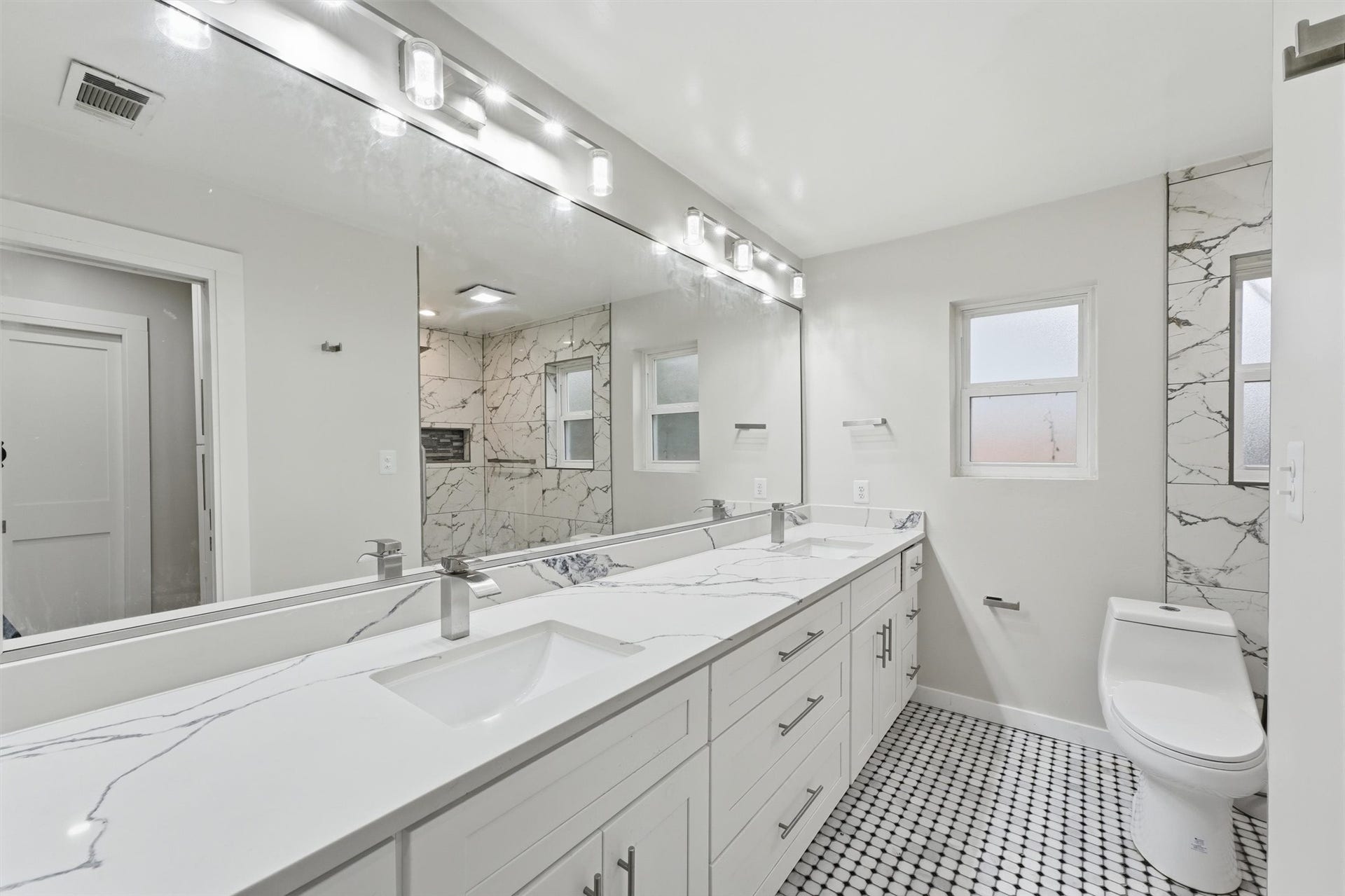 1718 Laurel Springs Lane, Kingwood, TX 77339 The third bathroom offers a double vanity with generous counterspace and storage, a large wall mirror, and patterned black-and-white tile flooring.
