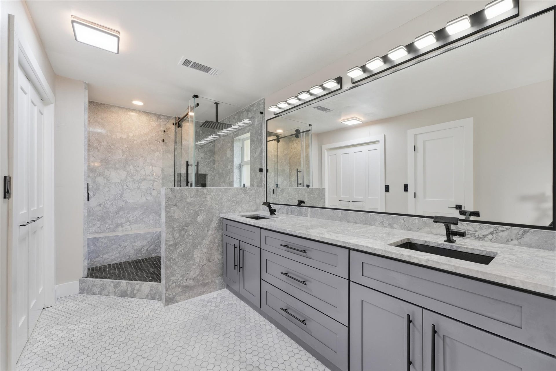 1718 Laurel Springs Lane, Kingwood, TX 77339 The second primary suite's private bathroom features a double vanity with black fixtures, a tub and shower combination with a glass enclosure, quartzite walls, and plenty of cabinet storage.