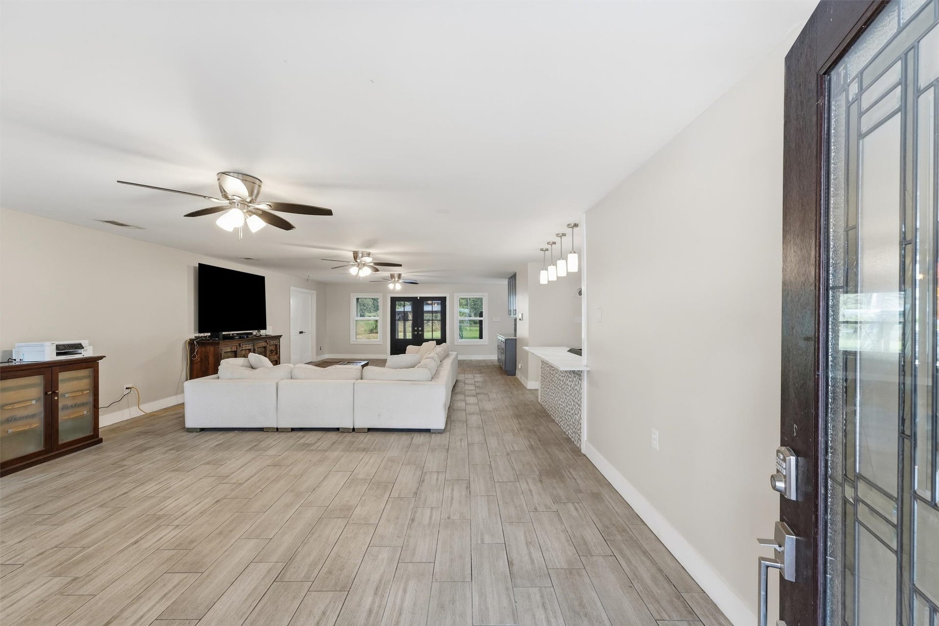 1718 Laurel Springs Lane, Kingwood, TX 77339 Spacious, open-concept living area with wood-like tile flooring, ceiling fans, and a clear view into kitchen and dining area.