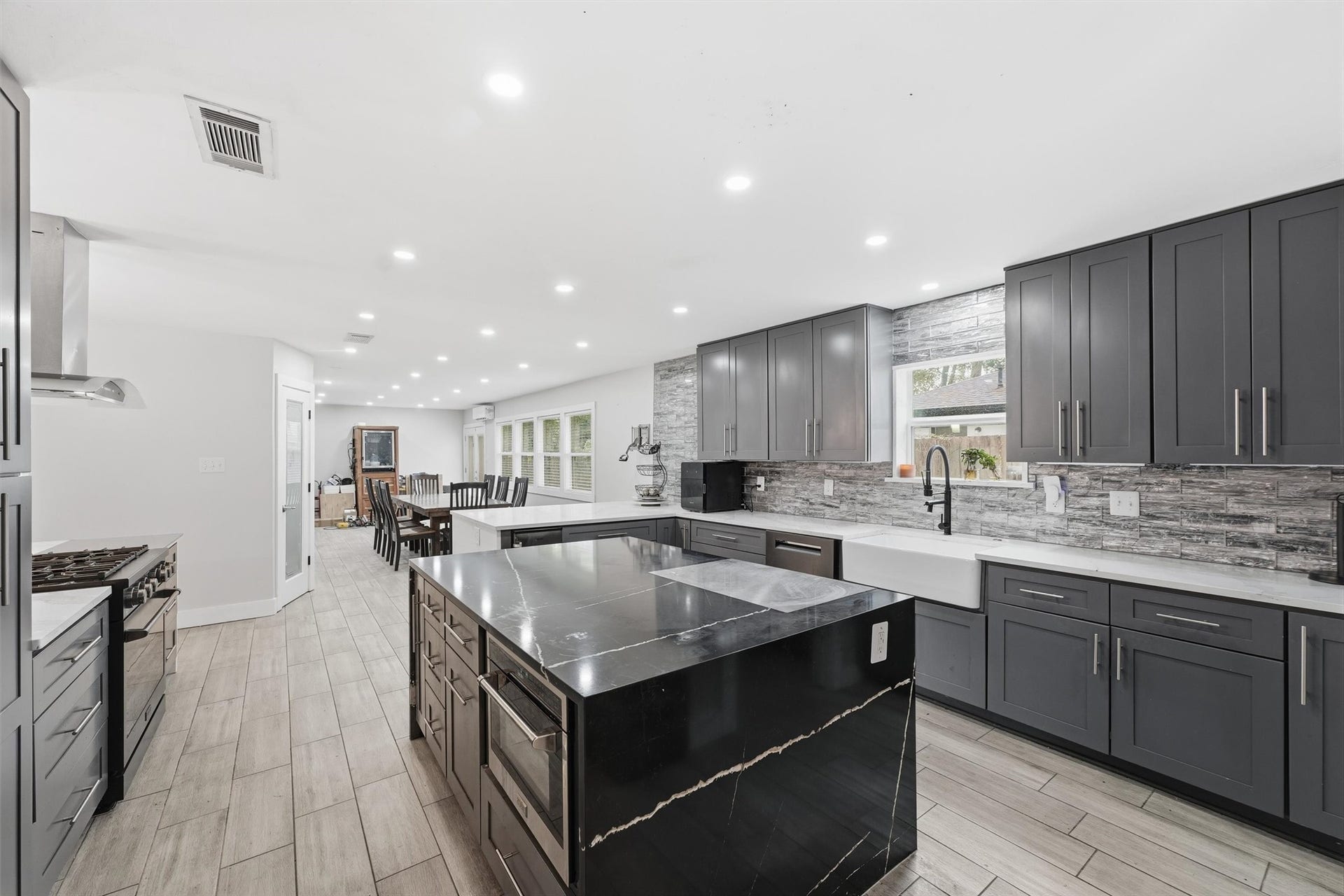 1718 Laurel Springs Lane, Kingwood, TX 77339 The center island features a contrasting dark quartzite countertop, built-in microwave, and additional storage, while quartz countertops and a farmhouse-style sink complete the back wall of the kitchen.