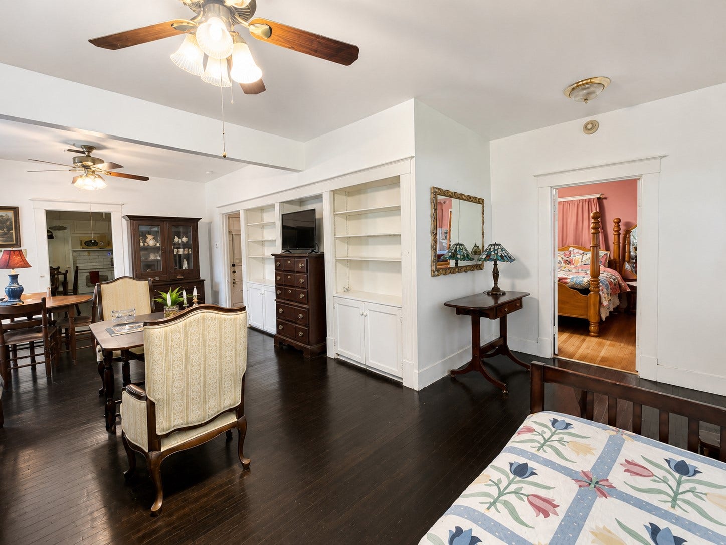 Another view highlights the rooms generous proportions, built-in shelving and cabinetry, and dark wood flooring. Multiple windows provide natural light, while the open layout offers flexibility for distinct seating and gathering areas.