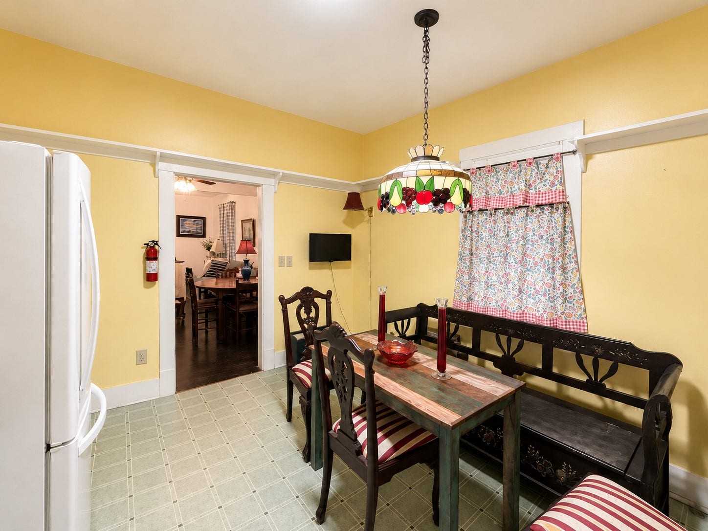 The kitchens dedicated dining area offers comfortable space for everyday meals and gatherings, complemented by a distinctive stained-glass-style pendant light and a nearby window.