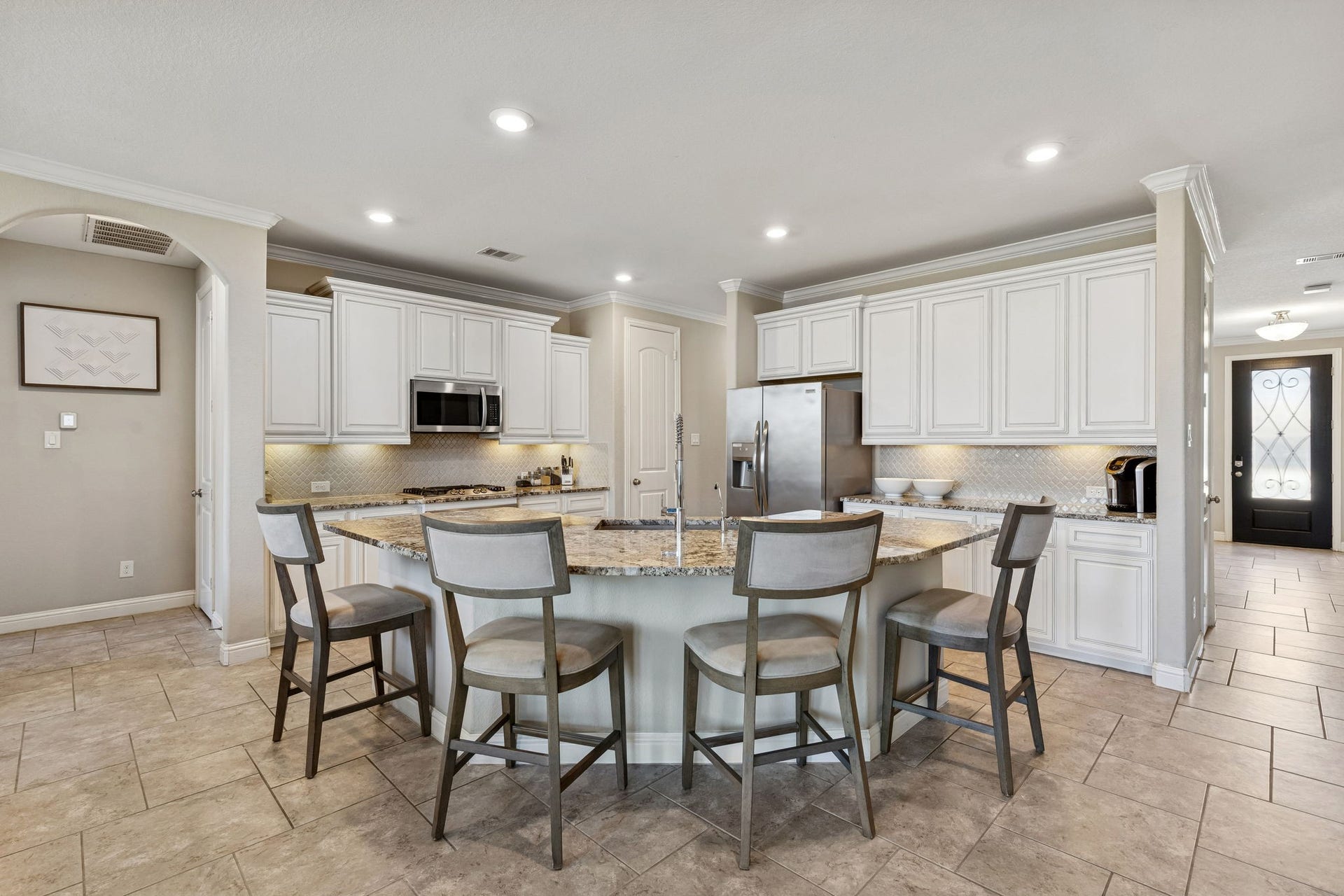 1619 Dove Ridge Drive, Katy, TX 77493 The chefs kitchen is open to the family room and features premium granite countertops and an expansive breakfast bar. Bright cabinetry is accented by coordinating backsplash and under-cabinet lighting.