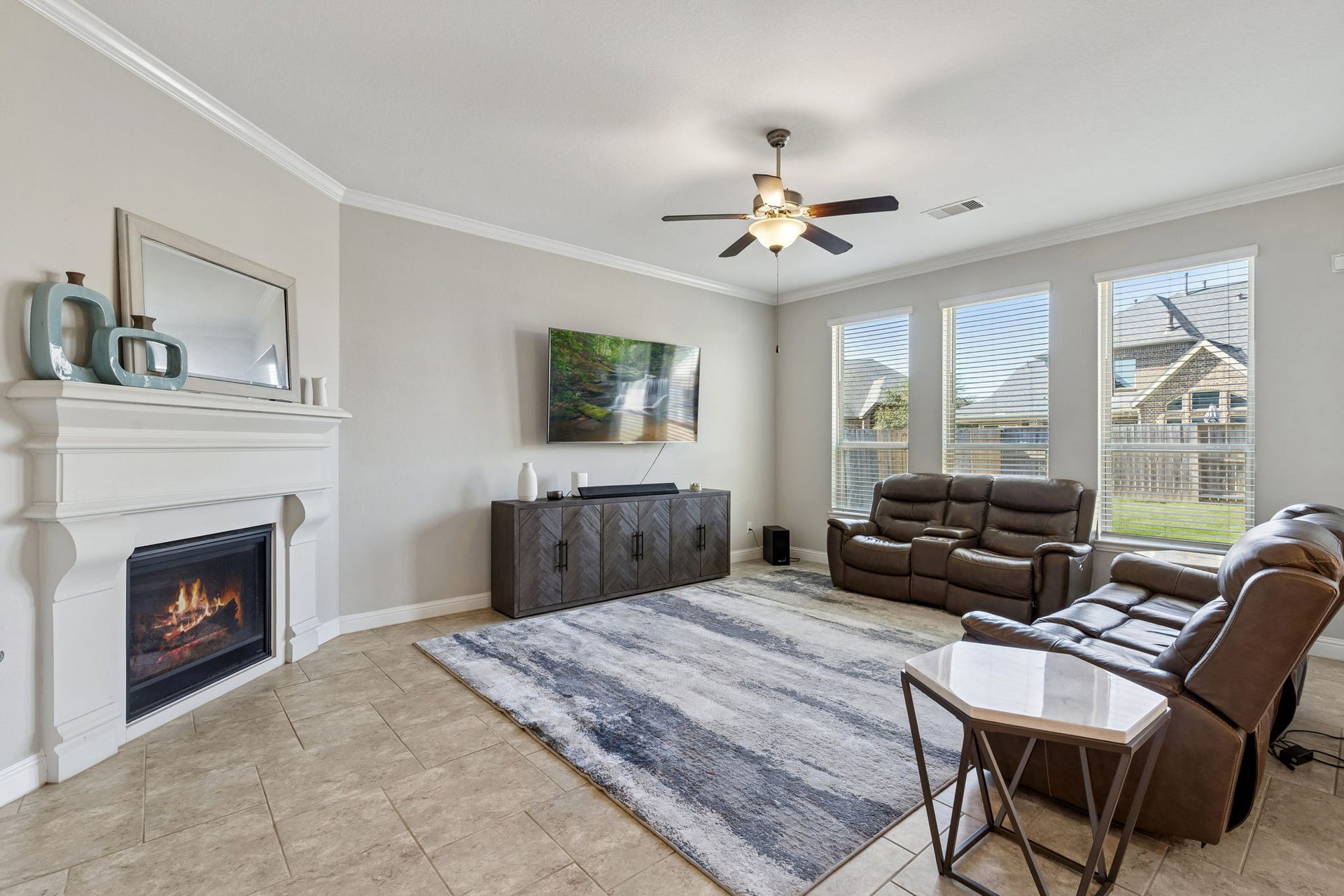 1619 Dove Ridge Drive, Katy, TX 77493 The spacious living area serves as a central hub, highlighted by a classic fireplace and tile flooring. Large windows fill the room with an airy atmosphere, offering views of the expansive backyard.