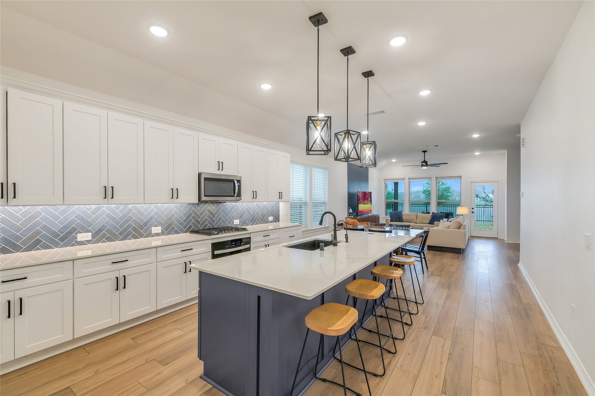 Stunning open-concept kitchen where everyday living comes with a view. The oversized island, quartz countertops, abundant cabinetry, and designer lighting open directly toward the living area and beautiful lake beyond.