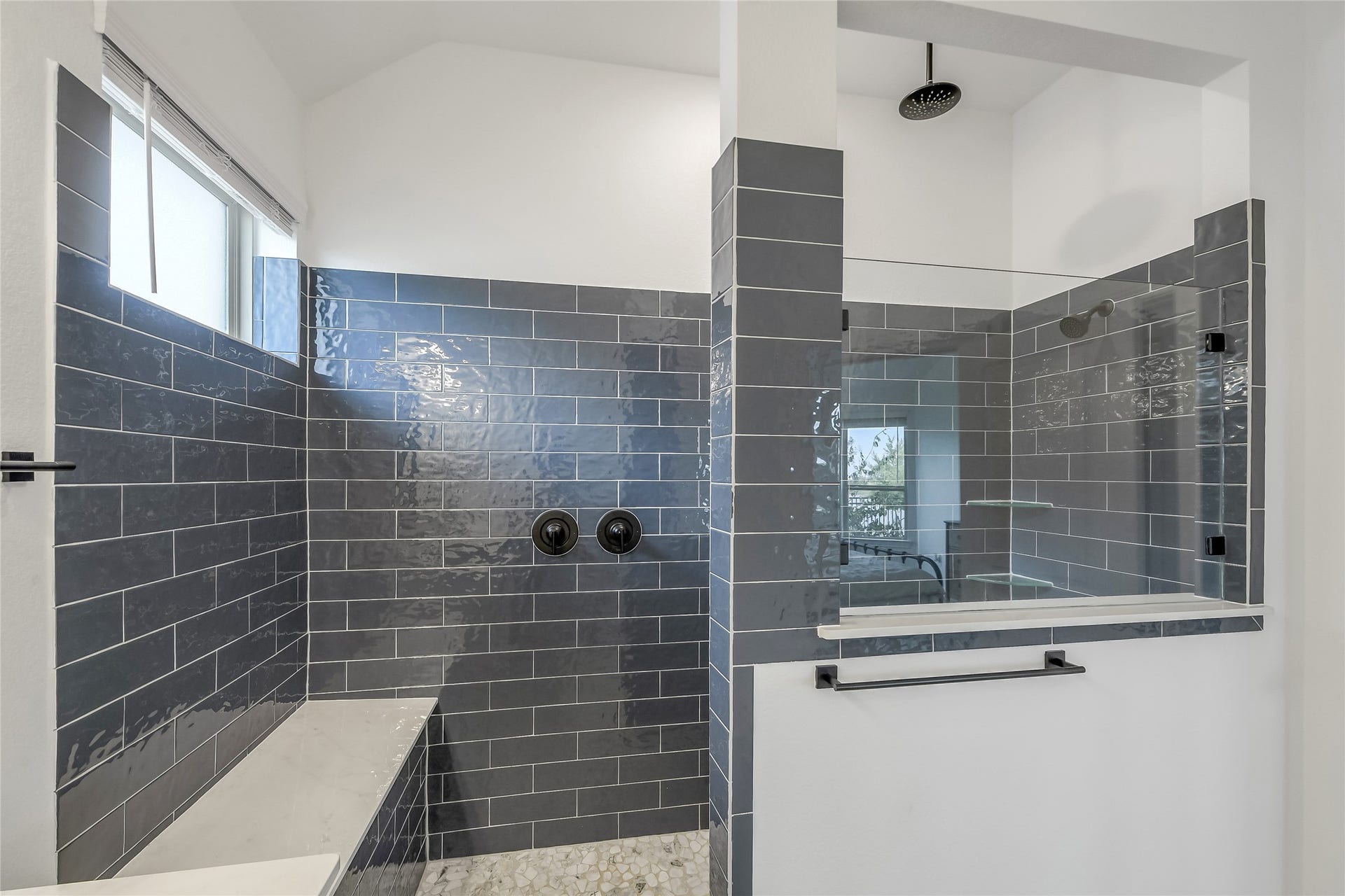 A true spa-inspired experience with an oversized walk-in shower, dramatic contemporary tilework, built-in bench, and glass enclosurean elevated everyday luxury within the primary suite.