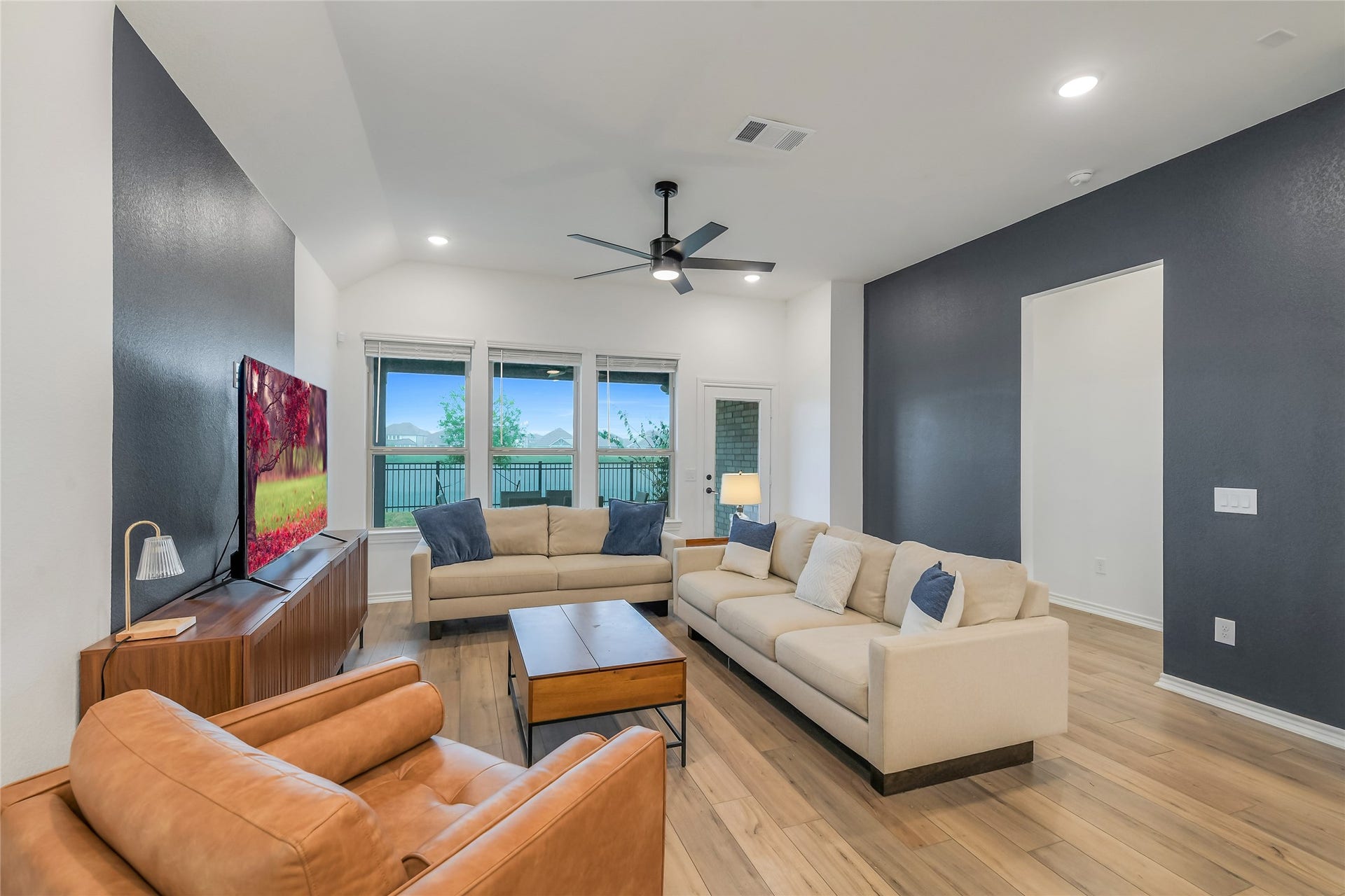 Waterfront living takes center stage with a wall of windows drawing your eye toward the lake. The spacious living room creates an inviting place to unwind, entertain, and enjoy the peaceful setting from inside your home