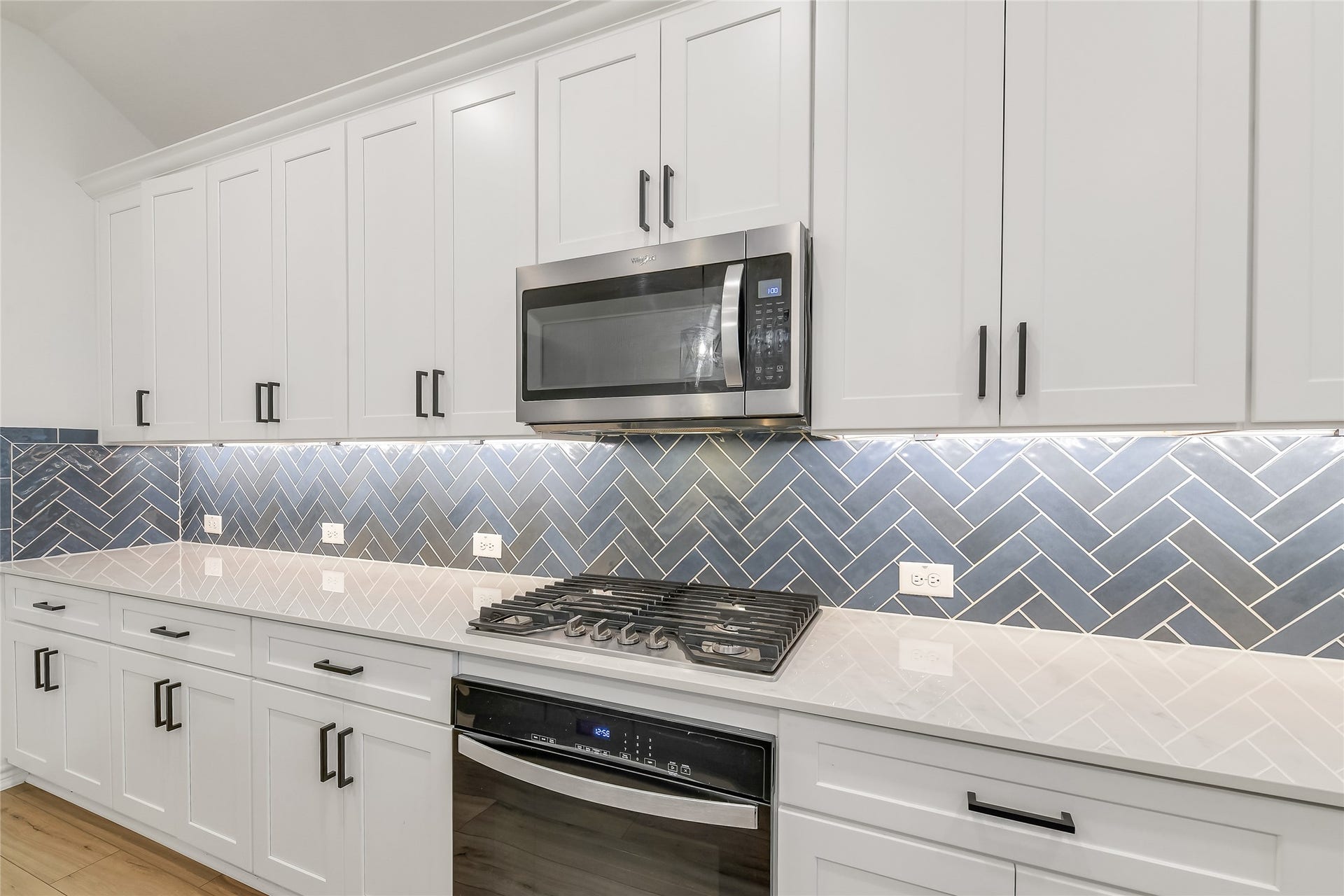 Beautifully finished kitchen features crisp white cabinetry, quartz countertops, stainless-steel appliances, and a stylish backsplash for a clean, contemporary look.