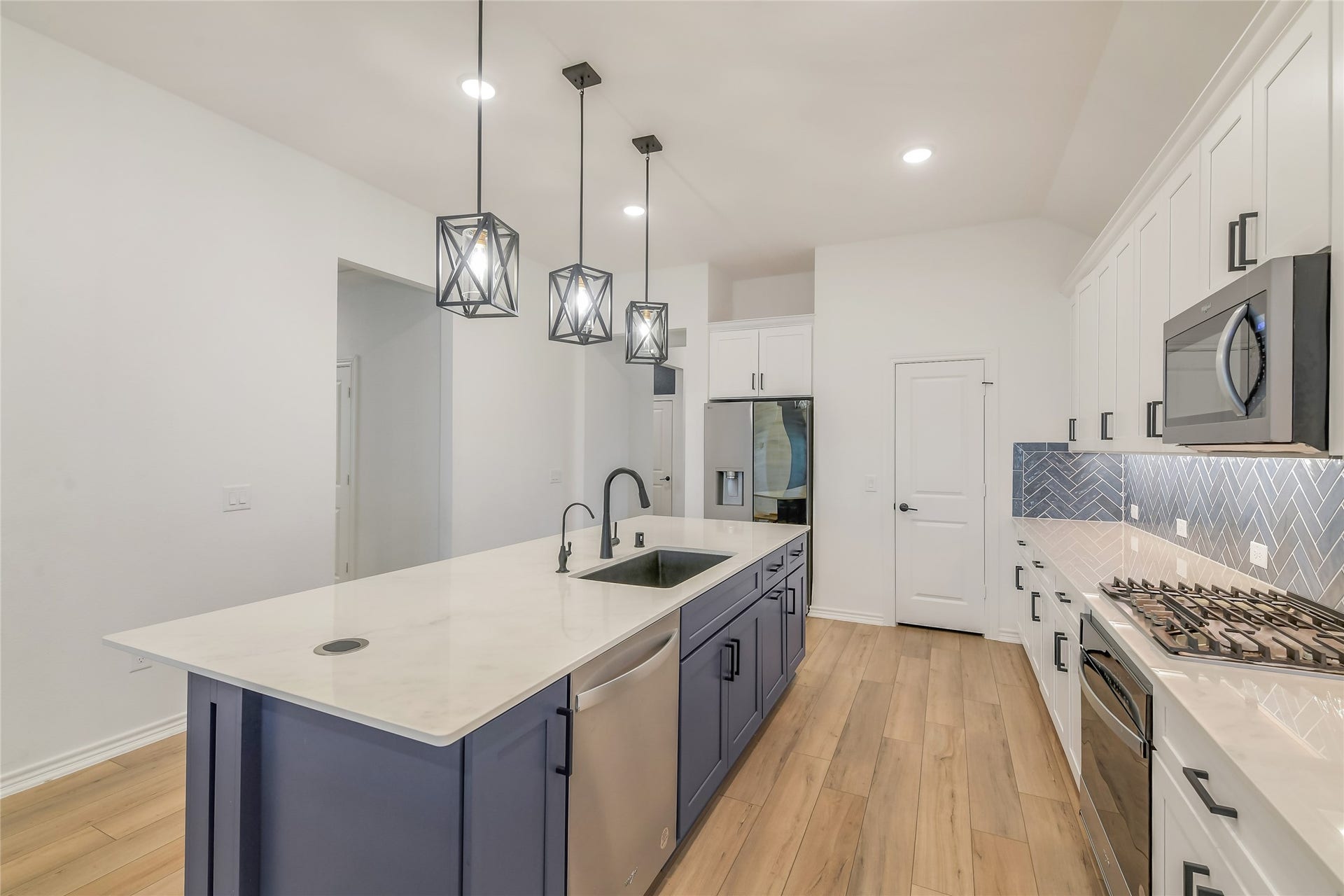 Bright, modern kitchen showcases quartz countertops, extensive cabinetry, stainless-steel appliances, designer pendant lighting, and a spacious center islandall within the homes open-concept layout.
