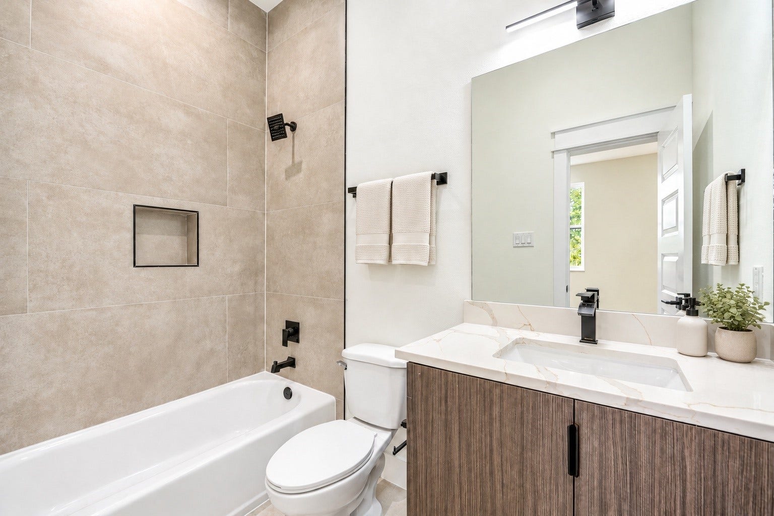 Third-floor ensuite full bath highlighting a clean white vanity, a clear view of the matte black plumbing fixtures, and floor-to-ceiling tile work over the tub.