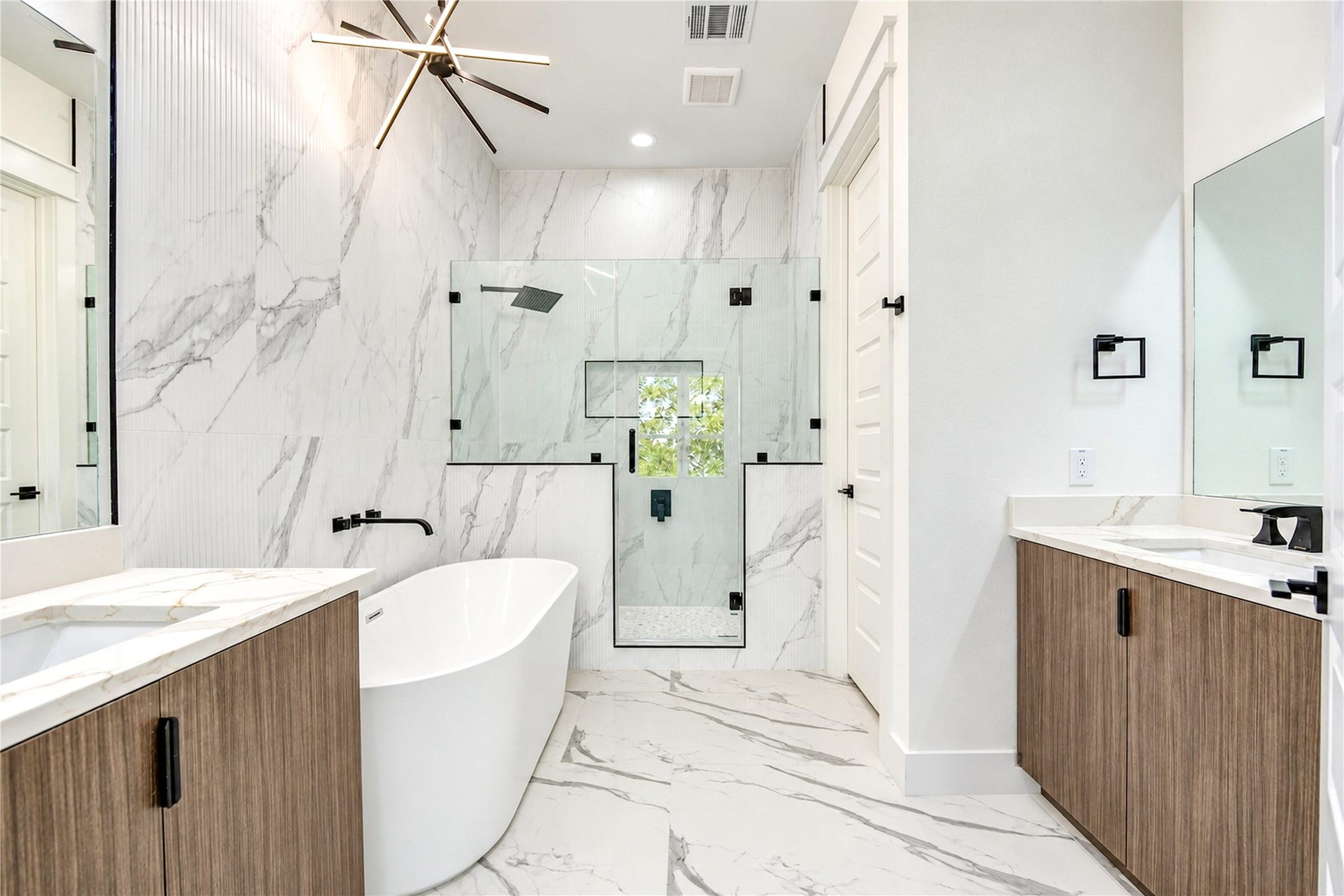 Primary bath with a freestanding tub, glass-enclosed rain shower, and vanity with a makeup area.