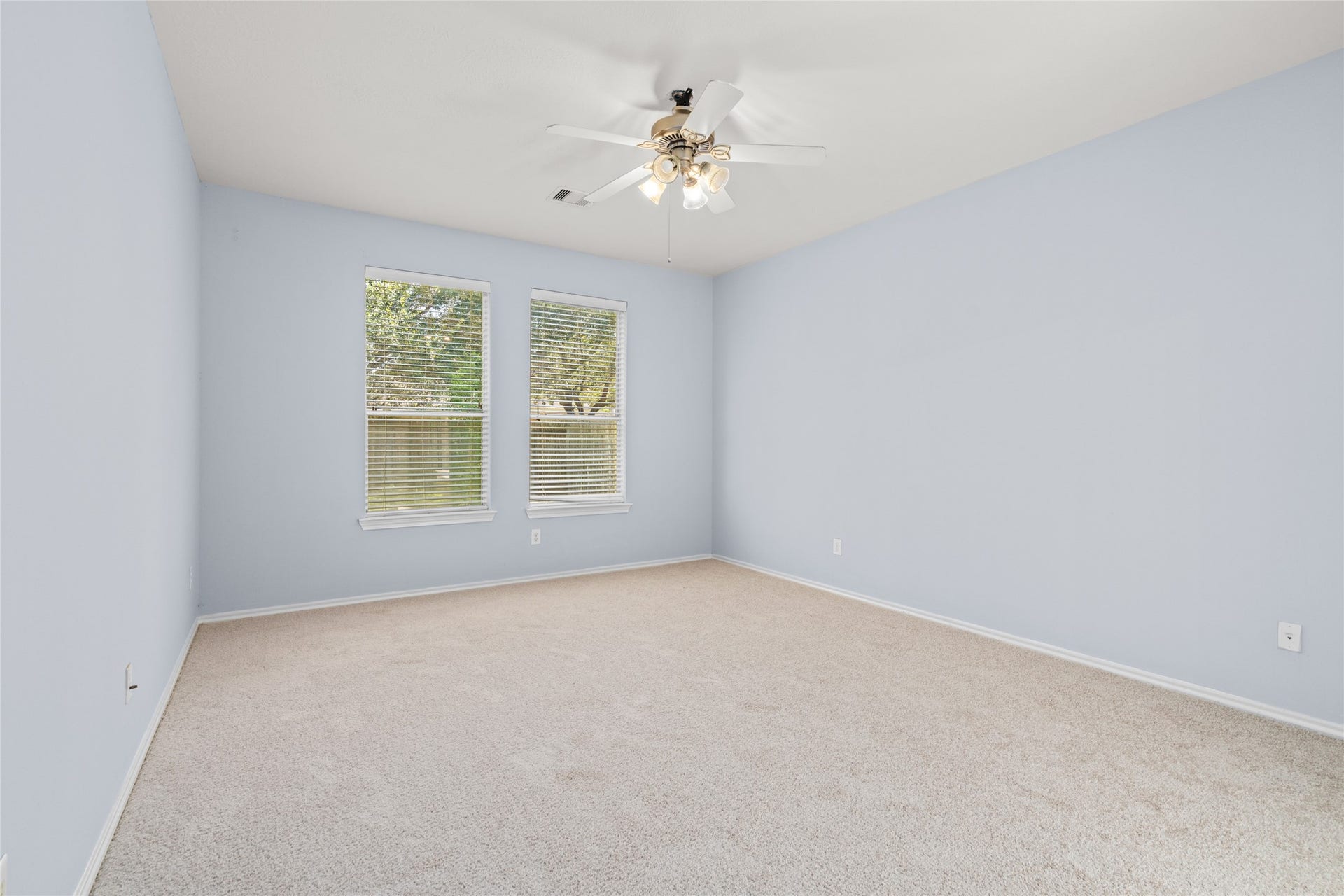 24519 Evangeline Springs Lane, Katy, TX 77494 Unfurnished primary bedroom with soft carpeting, natural light from two windows, and a ceiling fan. The open floor area allows buyers to plan their preferred bedroom layout and personalize the space to suit their needs.