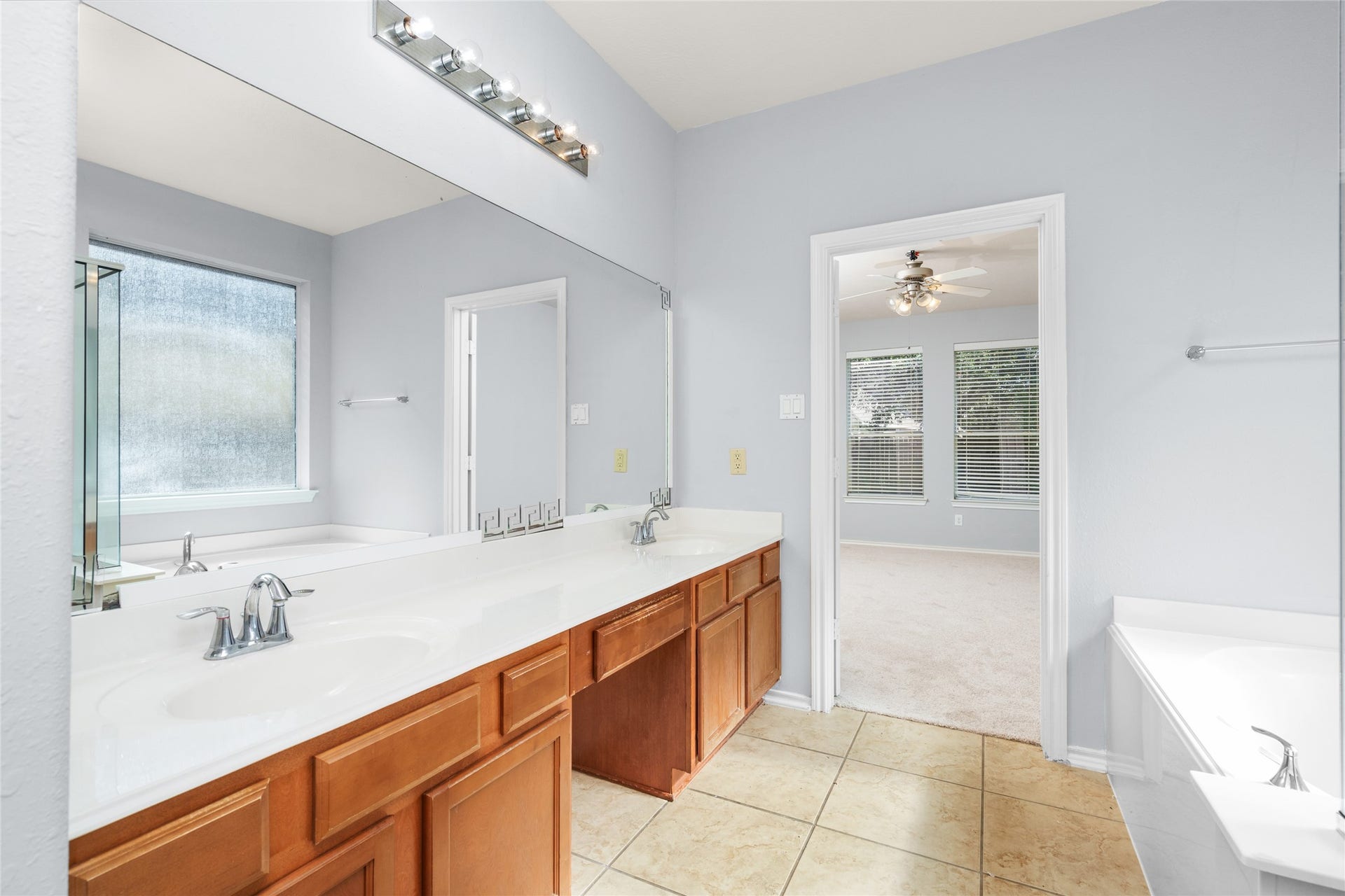 24519 Evangeline Springs Lane, Katy, TX 77494 Spacious primary bathroom with a long double vanity, ample counter space, and a large window for natural light. The two-sink arrangement offers added convenience for shared morning and evening routines.