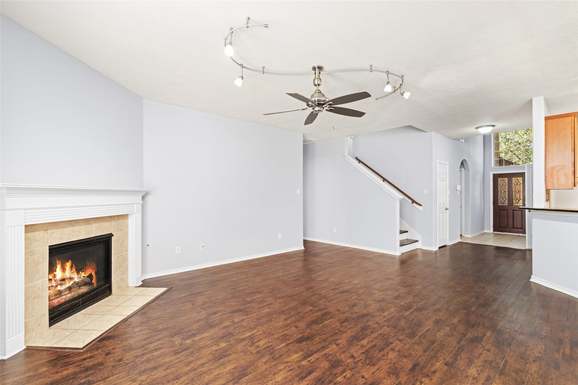 24519 Evangeline Springs Lane, Katy, TX 77494 Spacious living room featuring wood flooring, a corner fireplace, and an open staircase. The generous floor area creates room for everyday relaxation and entertaining, while the fireplace provides a natural focal point.