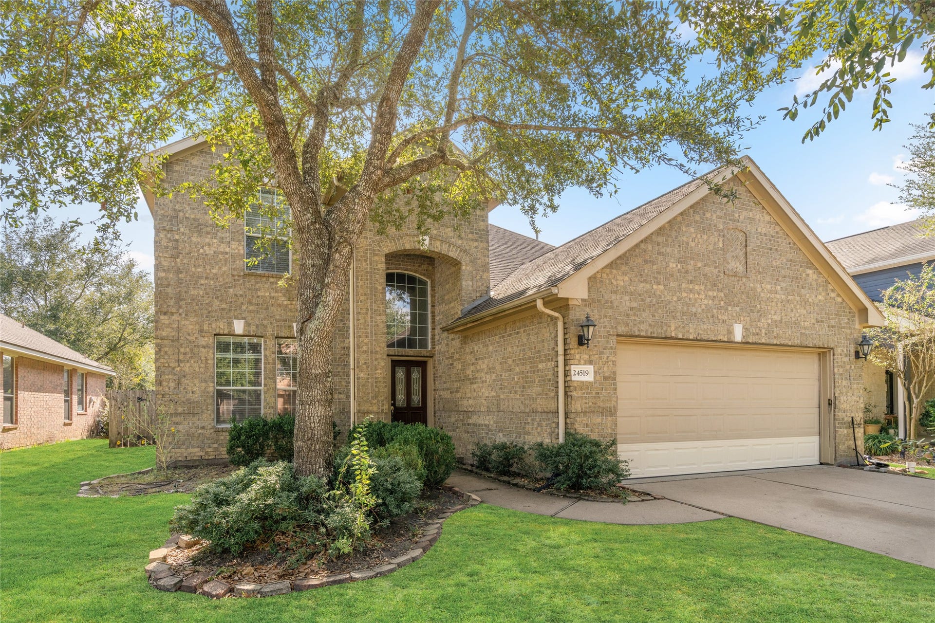 24519 Evangeline Springs Lane, Katy, TX 77494 Full front view of the two-story brick home, highlighting its arched entryway, mature trees, and landscaped grounds. The combination of traditional brickwork and established greenery gives the property timeless neighborhood appeal.