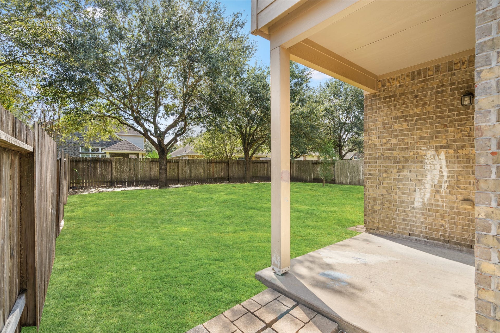 24519 Evangeline Springs Lane, Katy, TX 77494 Covered backyard patio overlooking a green lawn and mature trees. The shaded outdoor area provides a comfortable spot for outdoor dining, relaxing, or enjoying the backyard in warmer weather.