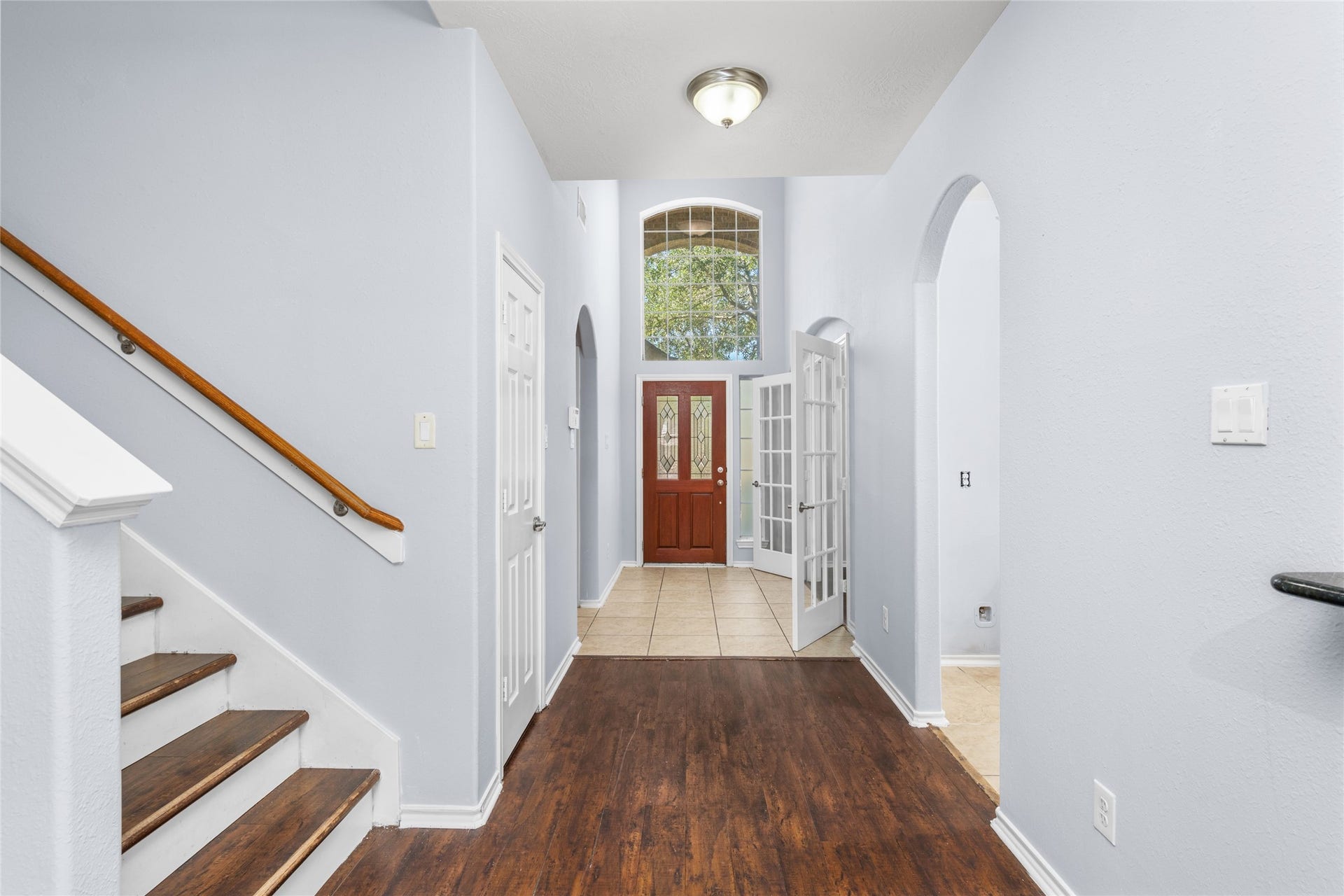 24519 Evangeline Springs Lane, Katy, TX 77494 Bright two-story entryway featuring warm wood flooring, a tall window above the front door, and a staircase with a wood handrail. The open vertical space creates an inviting arrival and connects the home's main living areas.