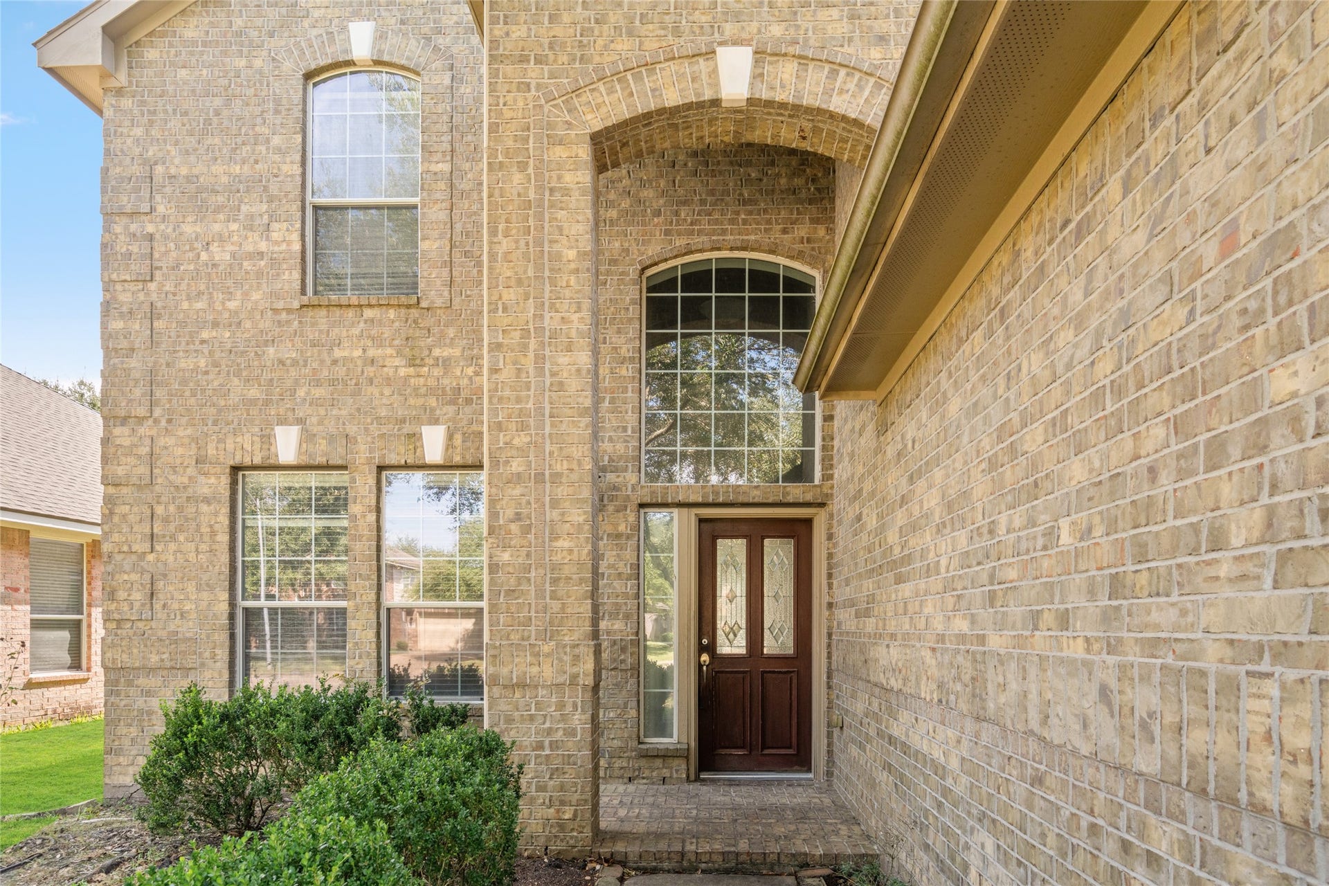 24519 Evangeline Springs Lane, Katy, TX 77494 Grand arched entry with tall windows and a covered front doorway, showcasing the home's architectural character. The elevated entry and natural light create a welcoming transition into the interior.