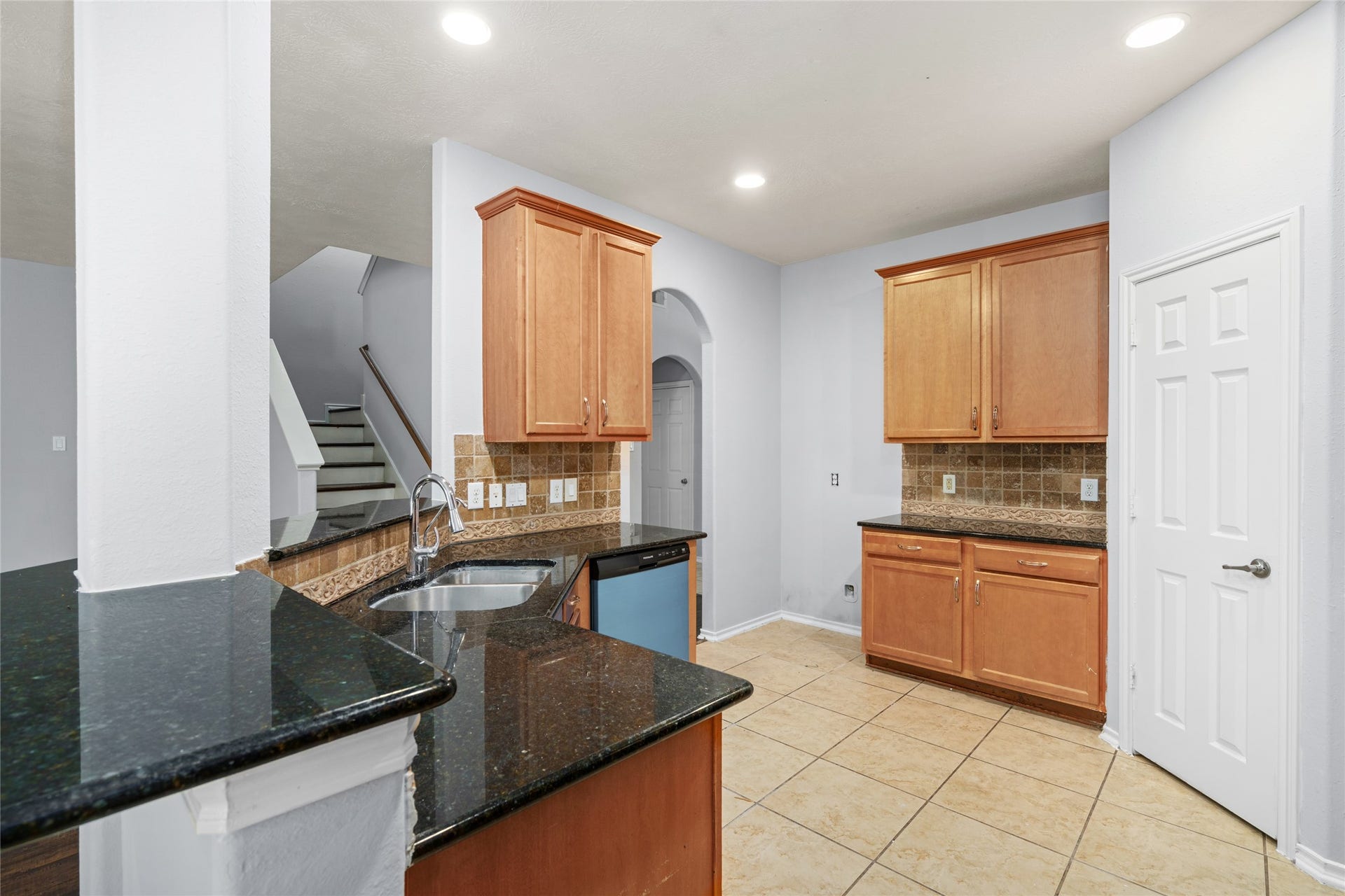24519 Evangeline Springs Lane, Katy, TX 77494 Kitchen featuring warm wood cabinetry, black granite countertops, and a breakfast bar overlooking the adjoining living space. The counter area provides additional workspace for meal preparation and a convenient place for casual dining.