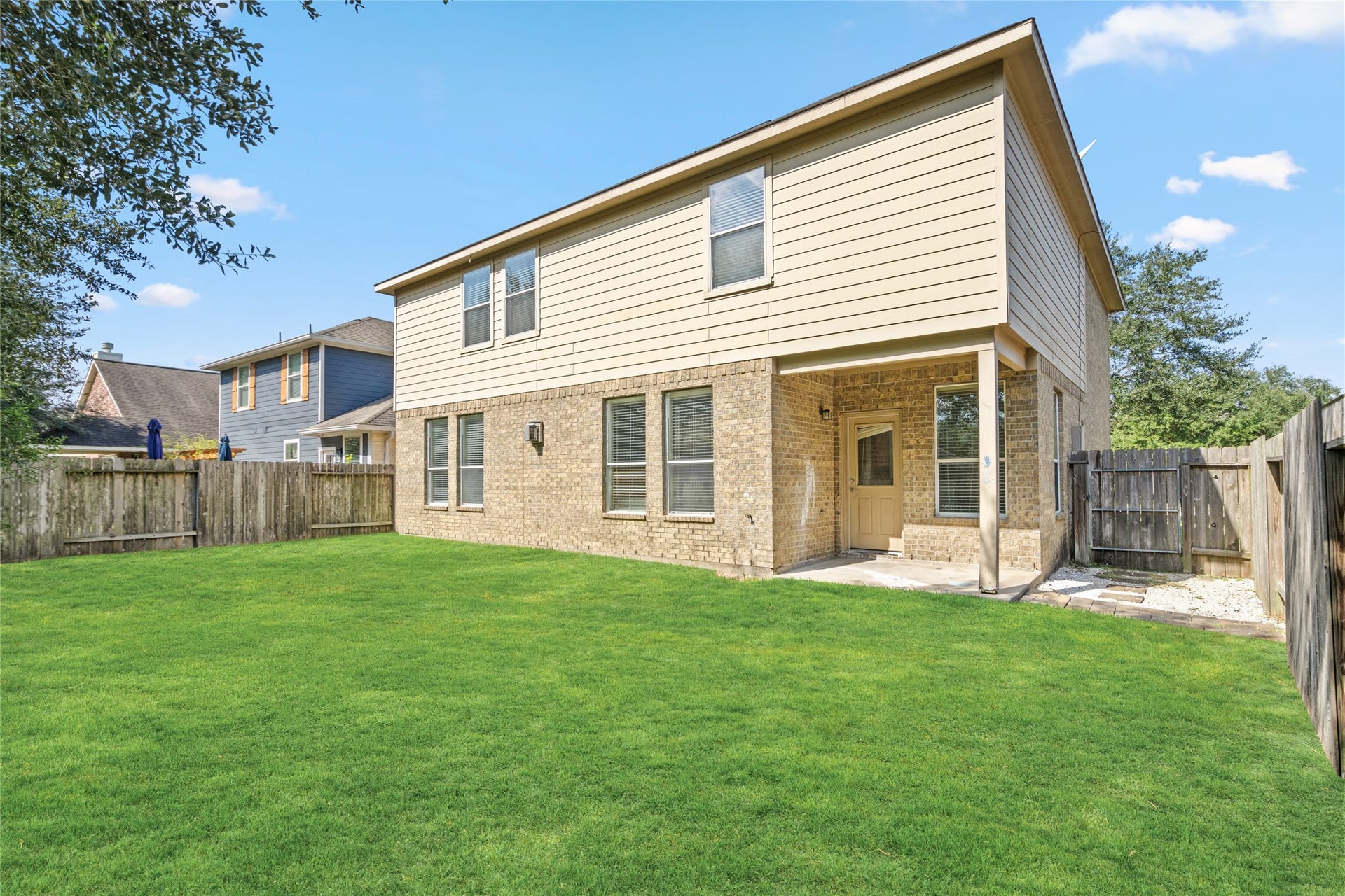 24519 Evangeline Springs Lane, Katy, TX 77494 Rear exterior view of the two-story home, highlighting the brick-and-siding faade, multiple windows, and expansive lawn. The view illustrates the home's backyard setting and the outdoor space available for everyday enjoyment.