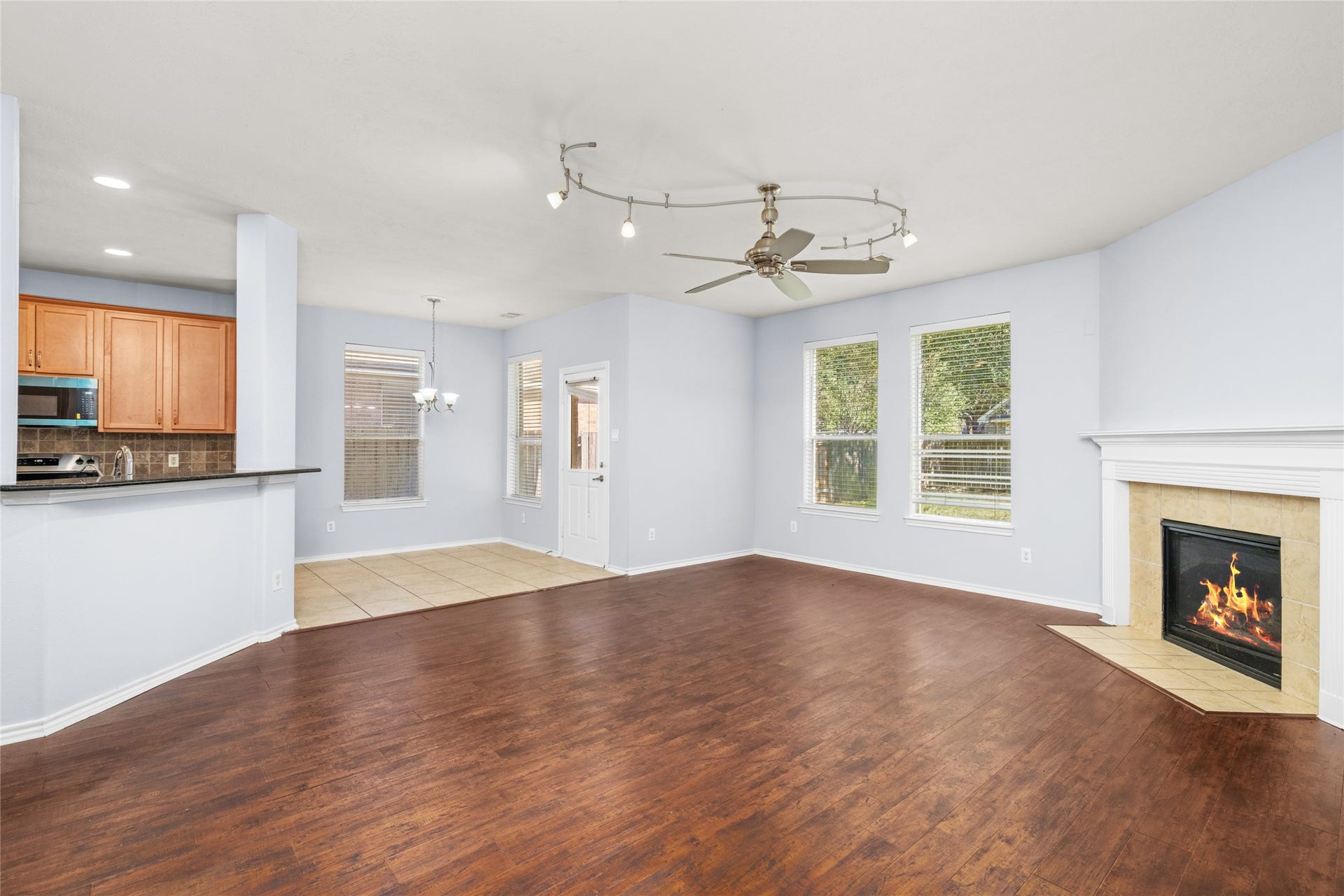 24519 Evangeline Springs Lane, Katy, TX 77494 Open-concept living area with wood flooring, a corner fireplace, and a broad view toward the kitchen and breakfast area. The connected layout supports easy conversation and movement between the home's main gathering spaces.