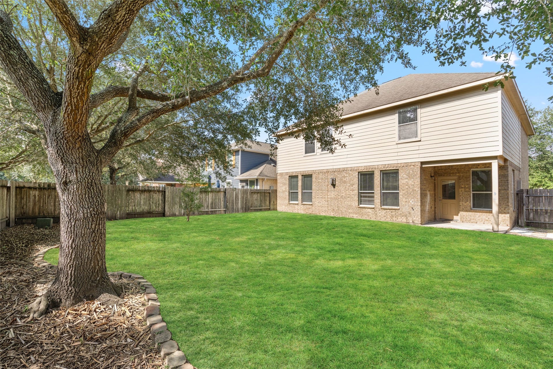 24519 Evangeline Springs Lane, Katy, TX 77494 Broad backyard view showcasing the green lawn, mature shade tree, and wood privacy fencing. The open outdoor space offers room for play, gardening, outdoor seating, or other activities suited to the household.