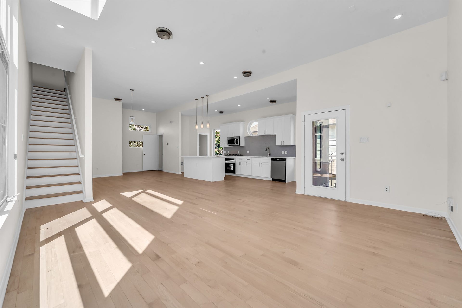 Spacious open-concept living area with hardwood floors, abundant natural light, and a modern brand new kitchen featuring stainless steel appliances.