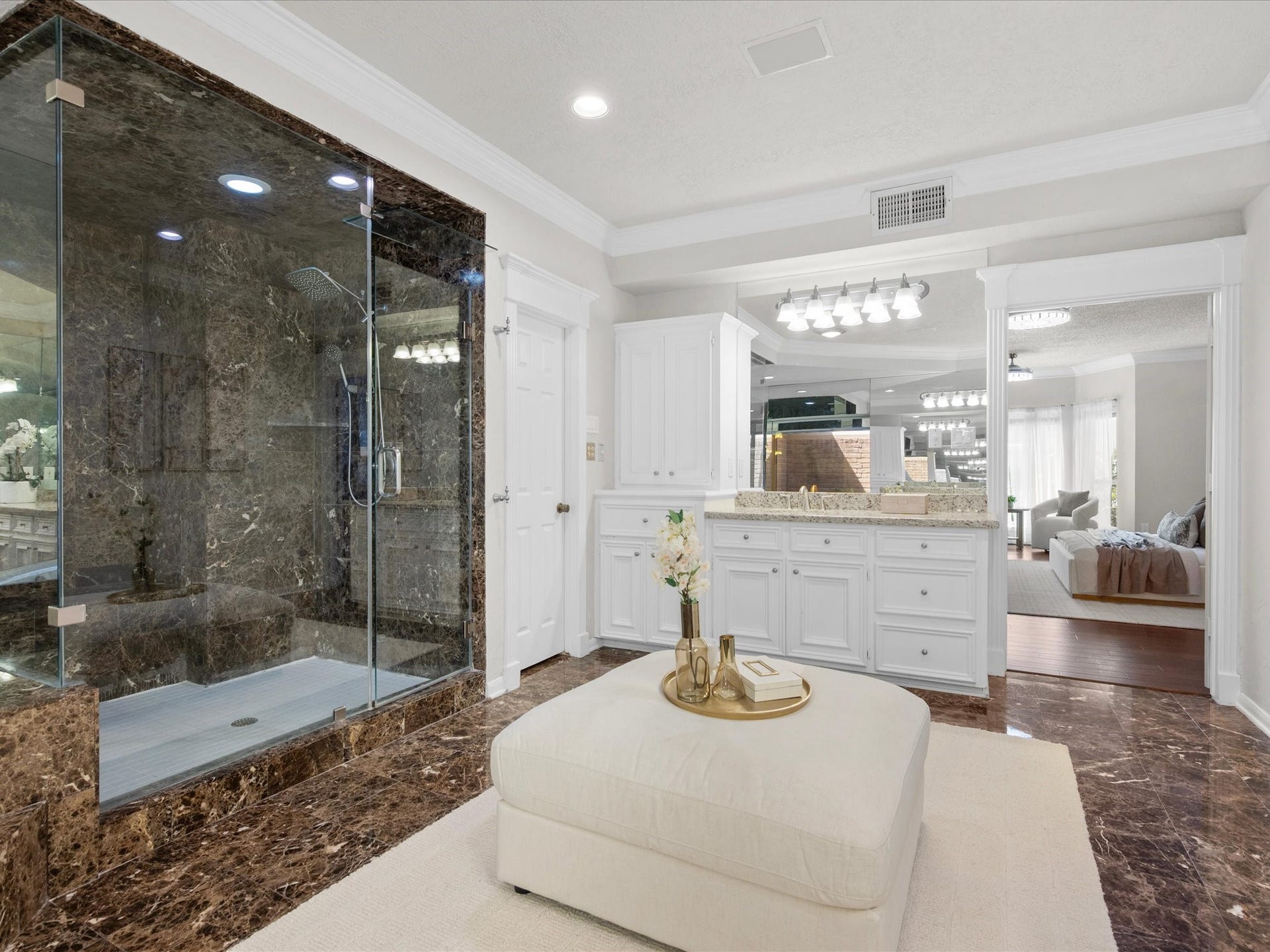 15902 Cumbria Drive, Spring, TX 77379 The walk in shower in the primary bath, floor to ceiling in dark marble with a rain shower head and a handheld. The second of the double sink vanity sits beside it, and the primary bedroom is right through the doorway. Showers and sleep stay close together.