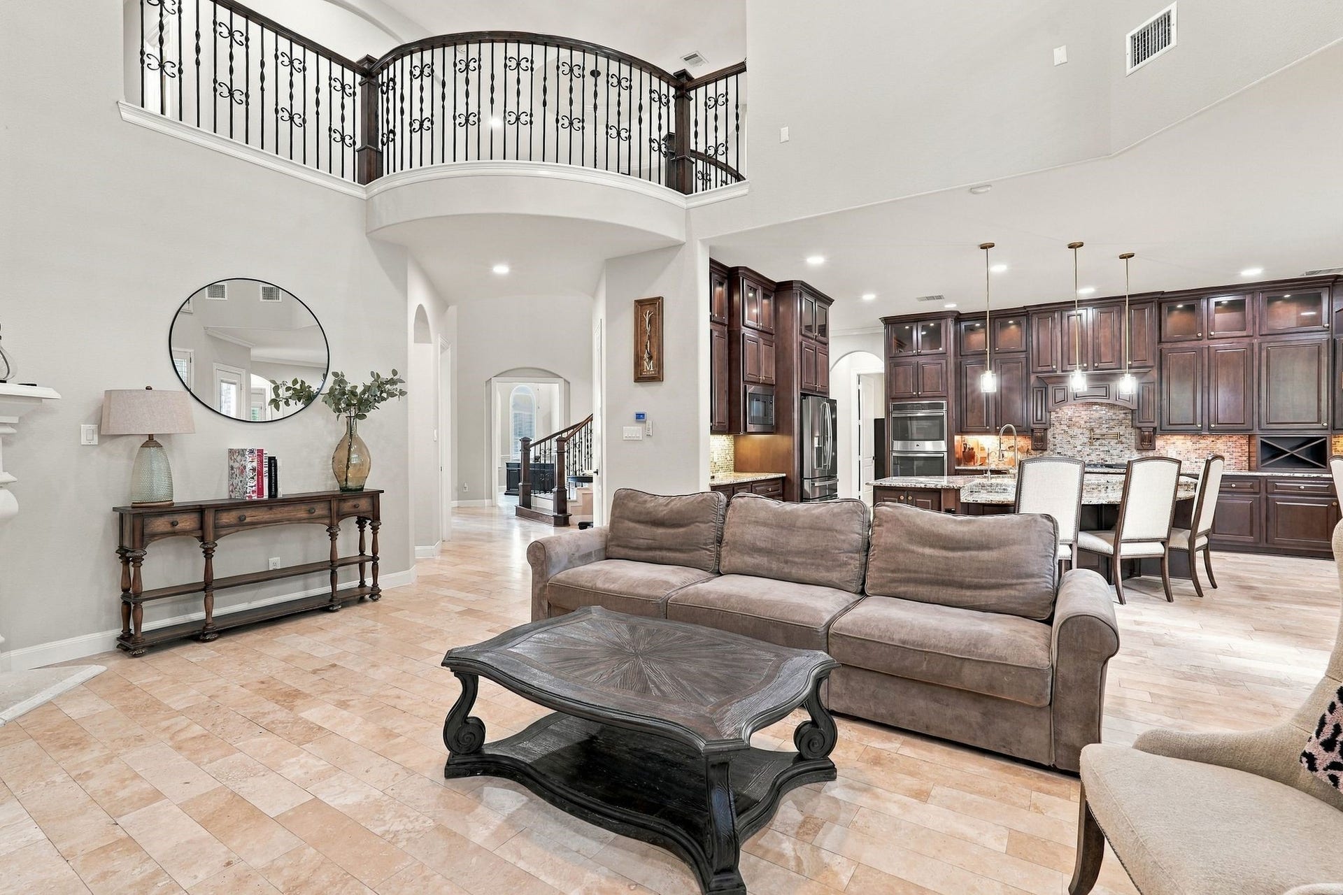 13714 Arcott Bend Drive, Tomball, TX 77377 Impressive in both scale and design, this expansive two-story living room showcases soaring ceilings, a dramatic curved second-story balcony with wrought-iron railings, and elegant travertine flooring. The grand, open-concept layout creates an incredible sense of space while flowing seamlessly into the gourmet kitchen, perfect for entertaining on any scale.