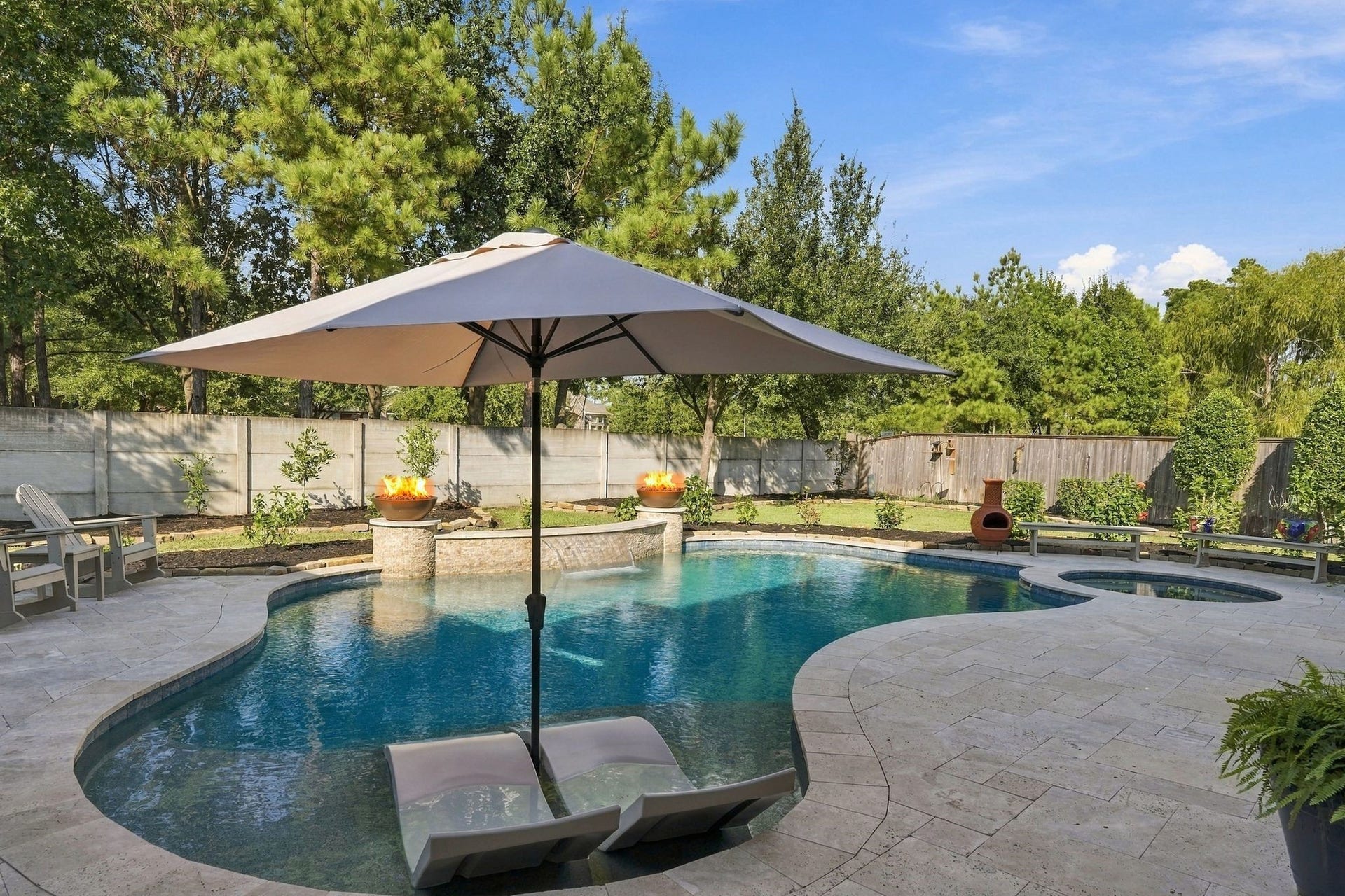 13714 Arcott Bend Drive, Tomball, TX 77377 Spectacular backyard oasis featuring a custom-designed resort-style pool with tanning ledge, in-water loungers, dramatic fire bowls, cascading water features, and an adjoining spa. Expansive decking and lush landscaping create an exceptional setting for outdoor entertaining and relaxation.