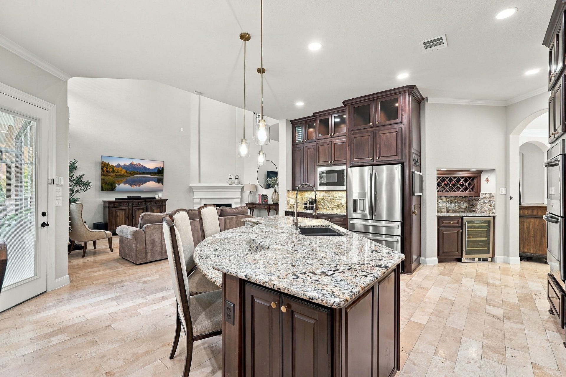 13714 Arcott Bend Drive, Tomball, TX 77377 Designed for elevated living and effortless entertaining, this exceptional gourmet kitchen showcases an expansive granite island, rich custom cabinetry, stainless steel appliances, and elegant pendant lighting. The open-concept design flows beautifully into the grand two-story living room, while a dedicated wine bar with built-in wine chiller adds a touch of luxury and sophistication.