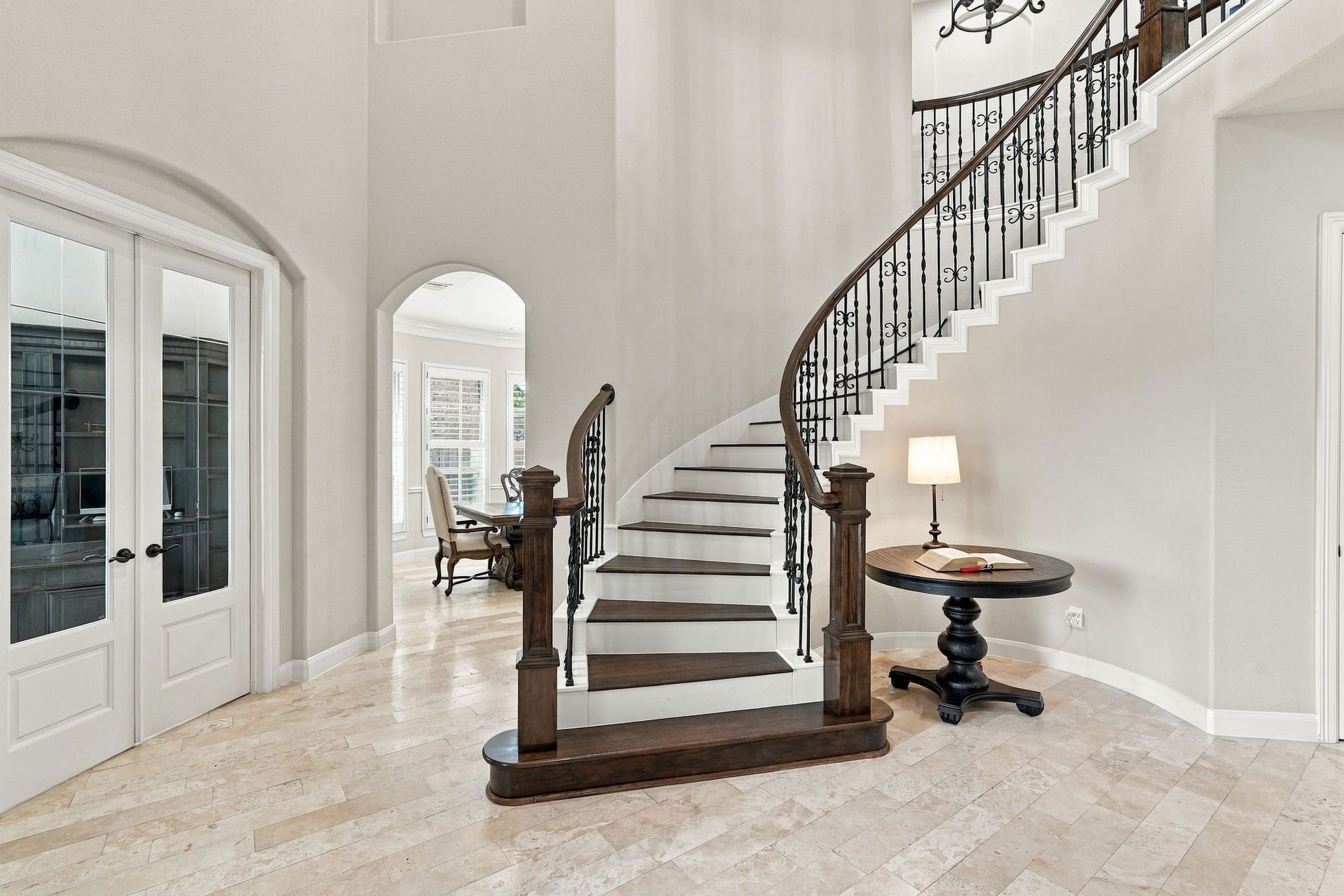 13714 Arcott Bend Drive, Tomball, TX 77377 Grand two-story foyer featuring a stunning curved staircase with rich wood treads, decorative wrought-iron balusters, elegant travertine flooring, and soaring ceilings. Beautiful architectural details create an impressive first impression upon entering this luxury home.