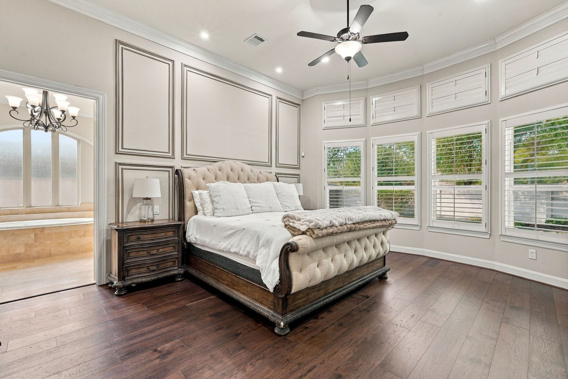 13714 Arcott Bend Drive, Tomball, TX 77377 Luxurious primary suite offers a serene retreat with beautiful hardwood flooring, elegant custom wall molding, and a wall of windows adorned with plantation shutters. The spacious design, abundant natural light, and direct access to the spa-inspired ensuite bathroom create the perfect blend of sophistication and comfort.