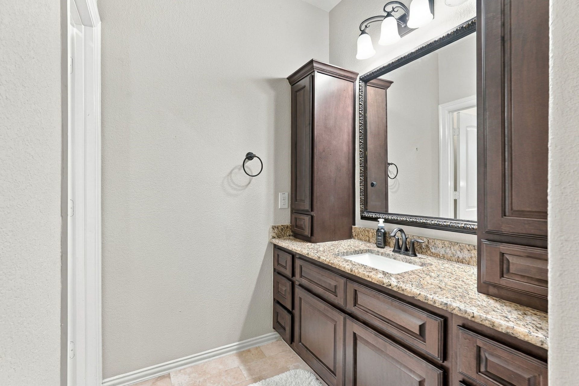 13714 Arcott Bend Drive, Tomball, TX 77377 Jack-and-Jill bathroom features a private vanity area with granite countertops, rich wood cabinetry, generous storage, and elegant framed mirror. A thoughtfully designed layout provides convenient access and privacy for the adjoining bedrooms.