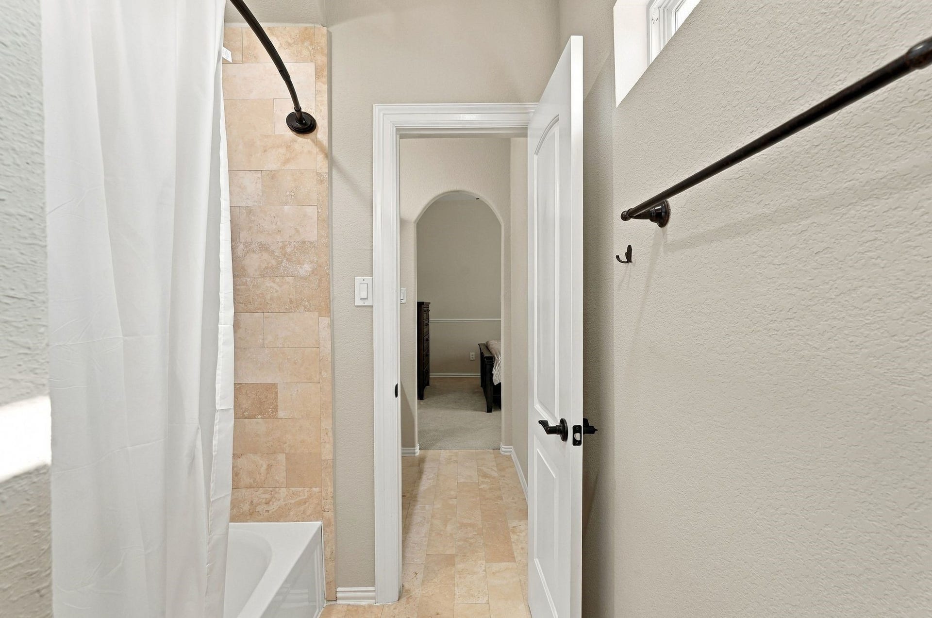 13714 Arcott Bend Drive, Tomball, TX 77377 Jack-and-Jill bathroom features a shared tub and shower combination with beautiful natural stone tile surround, coordinating tile flooring, and access to adjoining bedrooms. A functional design offering comfort and privacy.
