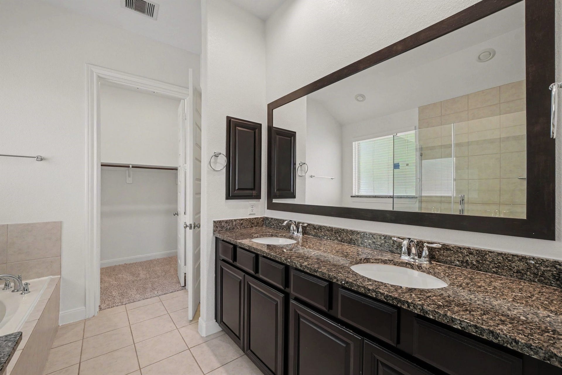 Primary bathroom with dual sinks and framed mirror