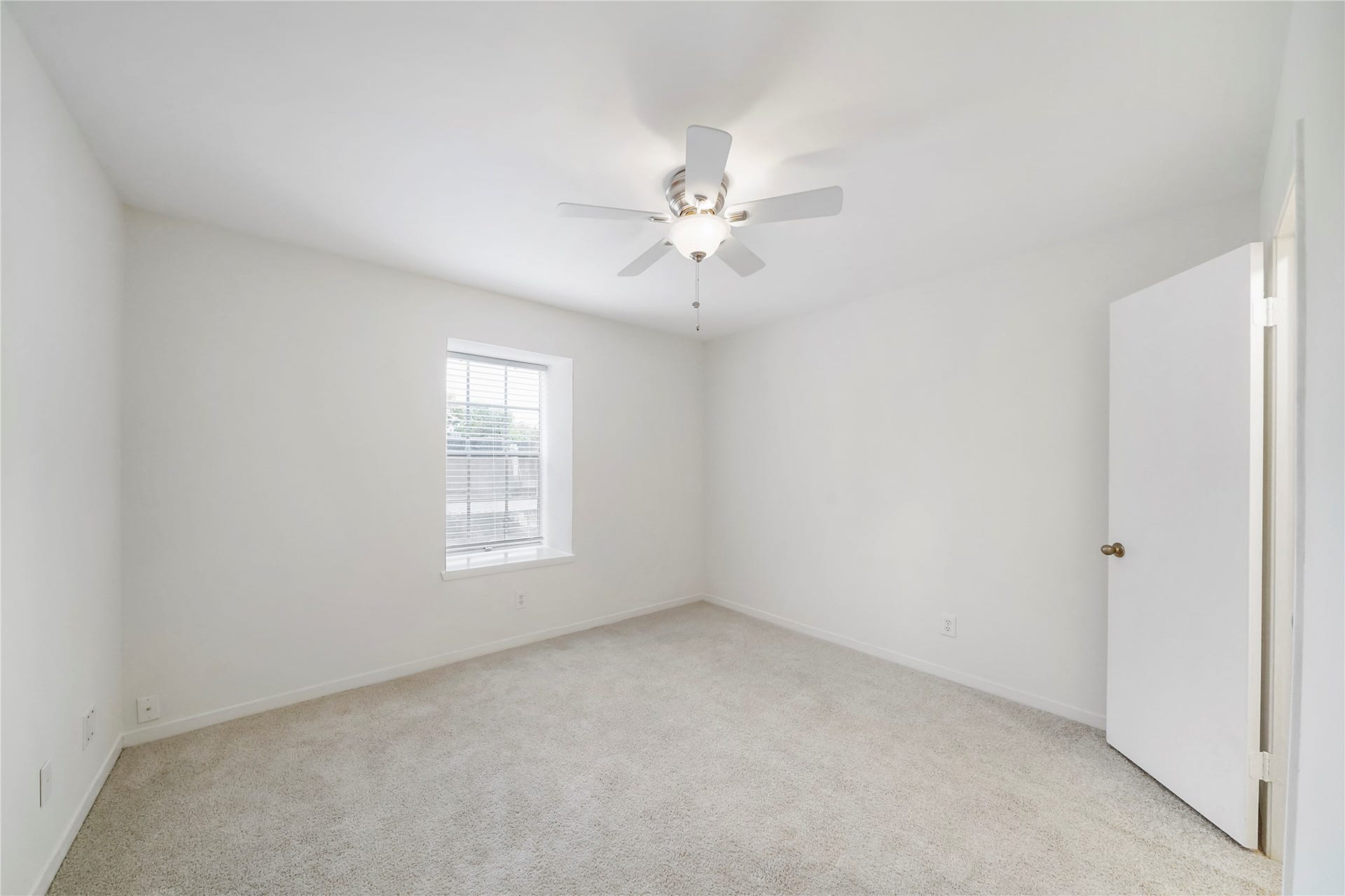Light and airy bedroom featuring soft neutral carpet, a ceiling fan with light kit, and a large picture window.