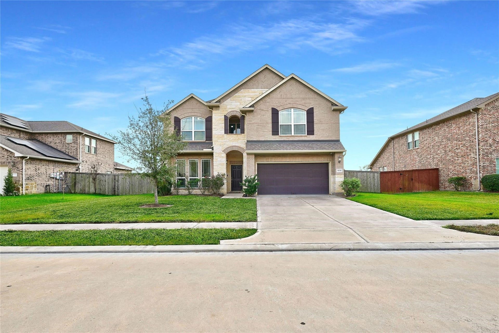 5936 Pearland Place, Pearland, TX 77581 This is a two-story, brick and stone house with a double garage and a well-maintained front yard. It features a wide driveway and is situated in a suburban neighborhood.