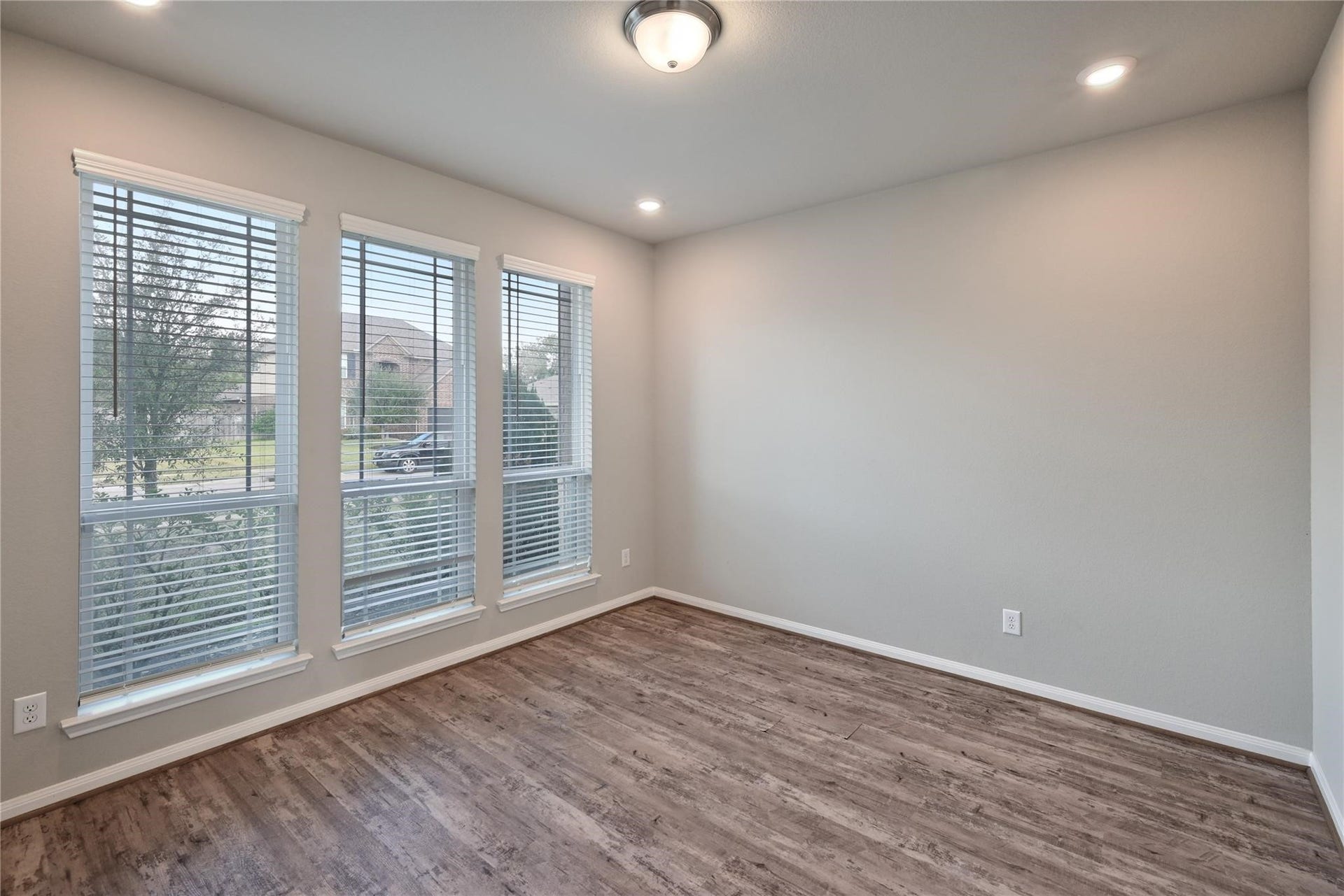 5936 Pearland Place, Pearland, TX 77581 This room features large windows with blinds, offering plenty of natural light. It has a neutral color scheme and hardwood flooring, providing a versatile space suitable for various uses. Recessed lighting and a central ceiling fixture enhance the illumination.