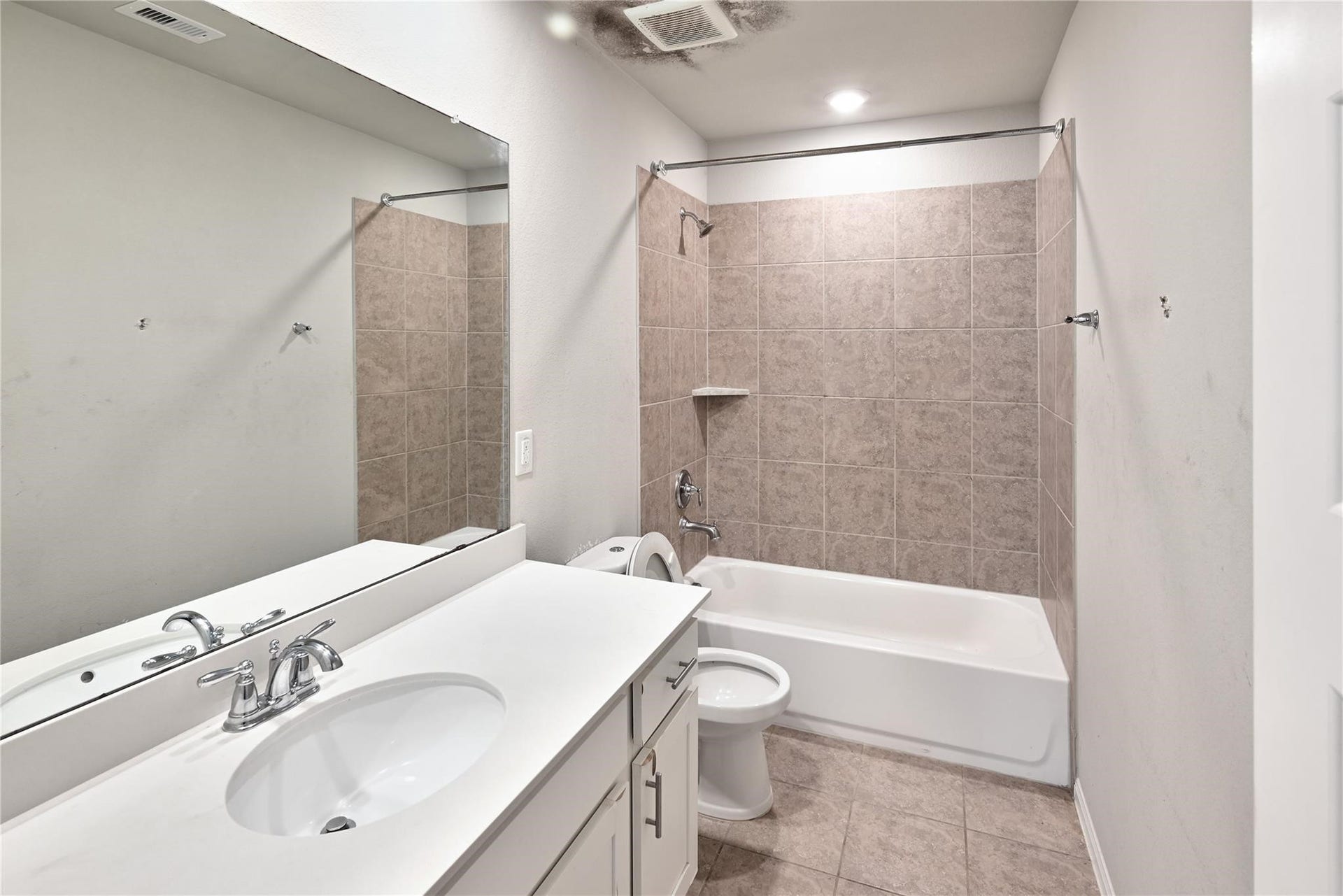 5936 Pearland Place, Pearland, TX 77581 This bathroom features a sleek vanity with a modern sink and faucet, a large mirror, and a bathtub with tile surround. The neutral color scheme creates a clean and inviting space.