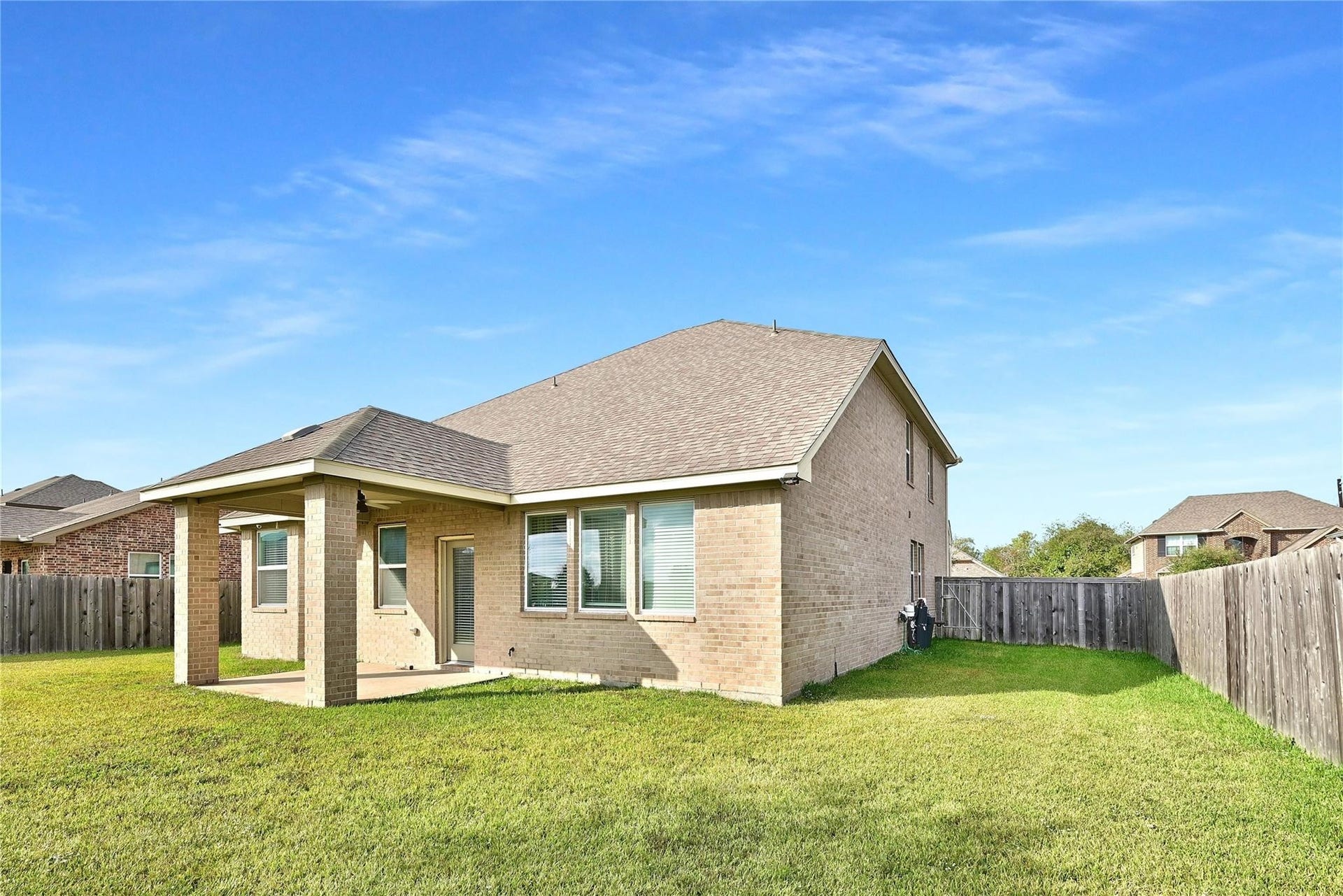 5936 Pearland Place, Pearland, TX 77581 This photo shows a two-story brick home with a fenced backyard and a covered patio, perfect for outdoor activities and privacy.