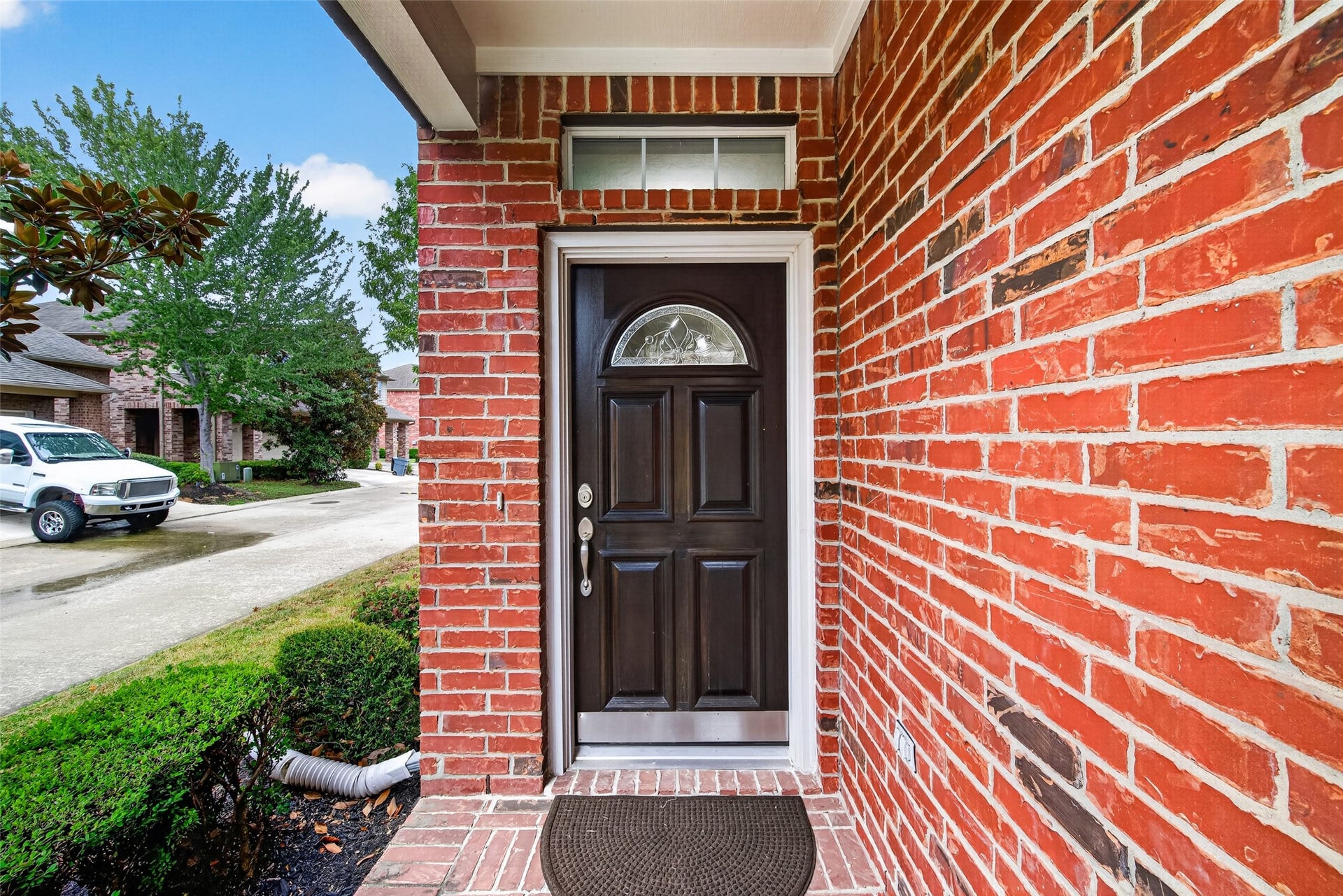 8910 Minola Oaks Drive, Houston, TX 77064 Charming red brick patio with transom window above a wood and leaded glass door welcomes guests.