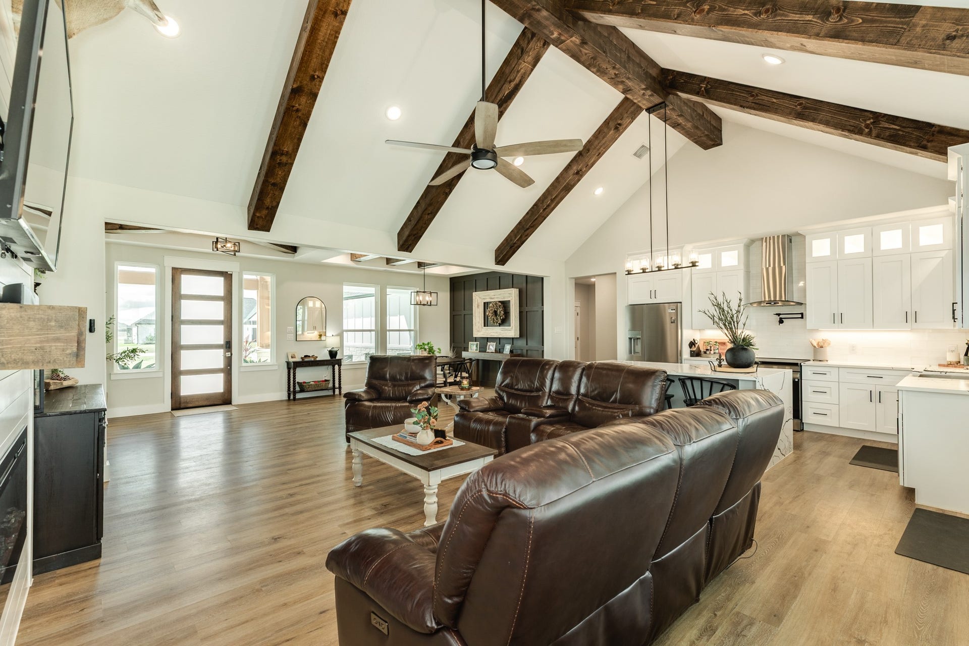 608 Angus Trail, Angleton, TX 77515 Spacious open-concept living area with vaulted ceilings and rustic wood beams. A modern kitchen with stainless steel appliances and elegant white cabinetry is perfect for entertaining and keeping the cook involved in activities